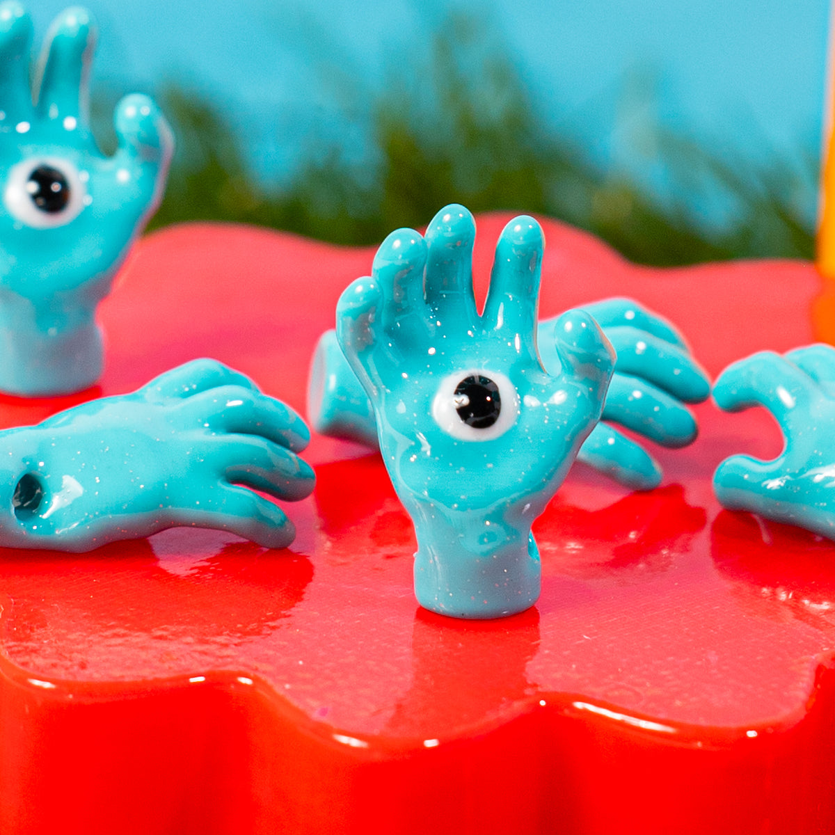 Blue hand kandi beads with eyeballs in the palms on a glossy red riser