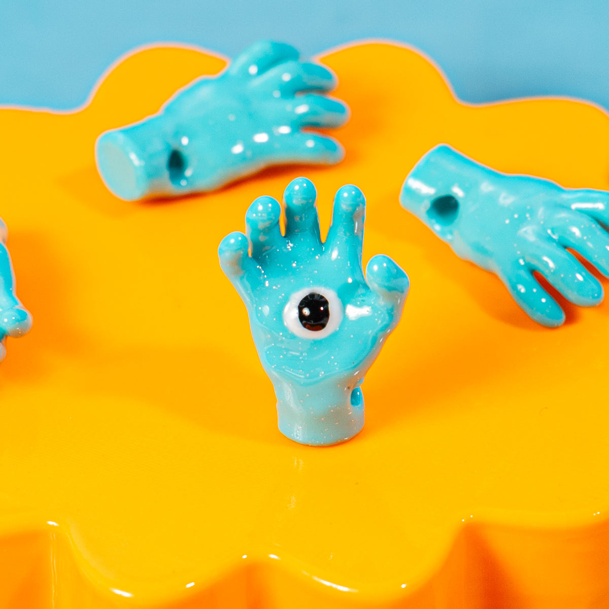 All seeing hand kandi beads on an orange riser against a blue backdrop