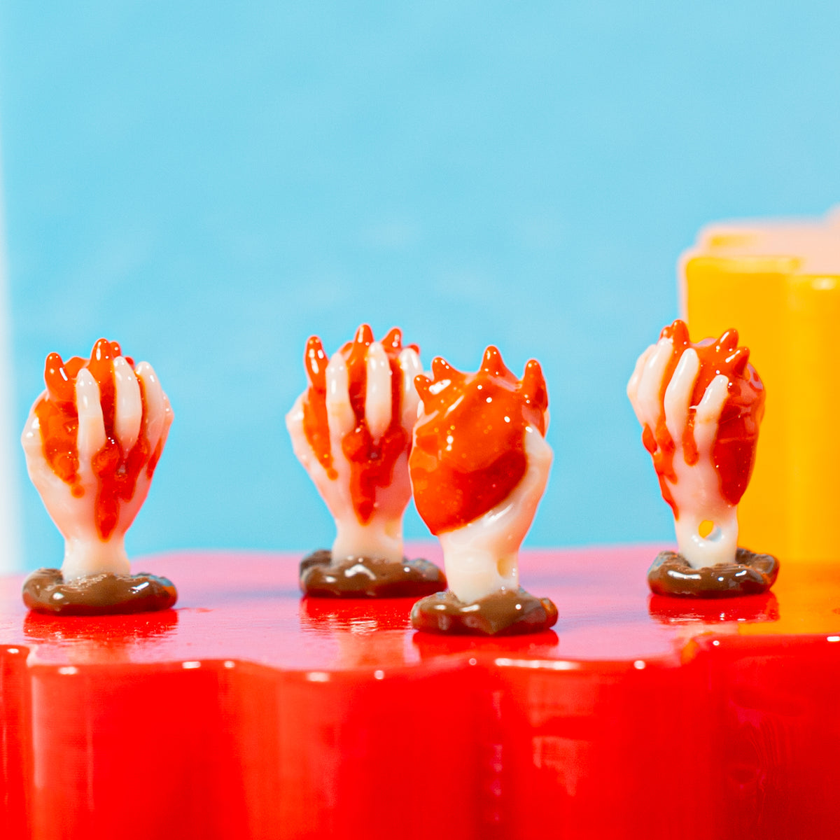 Row of anatomical heart hand kandi beads on a red riser against a blue backdrop
