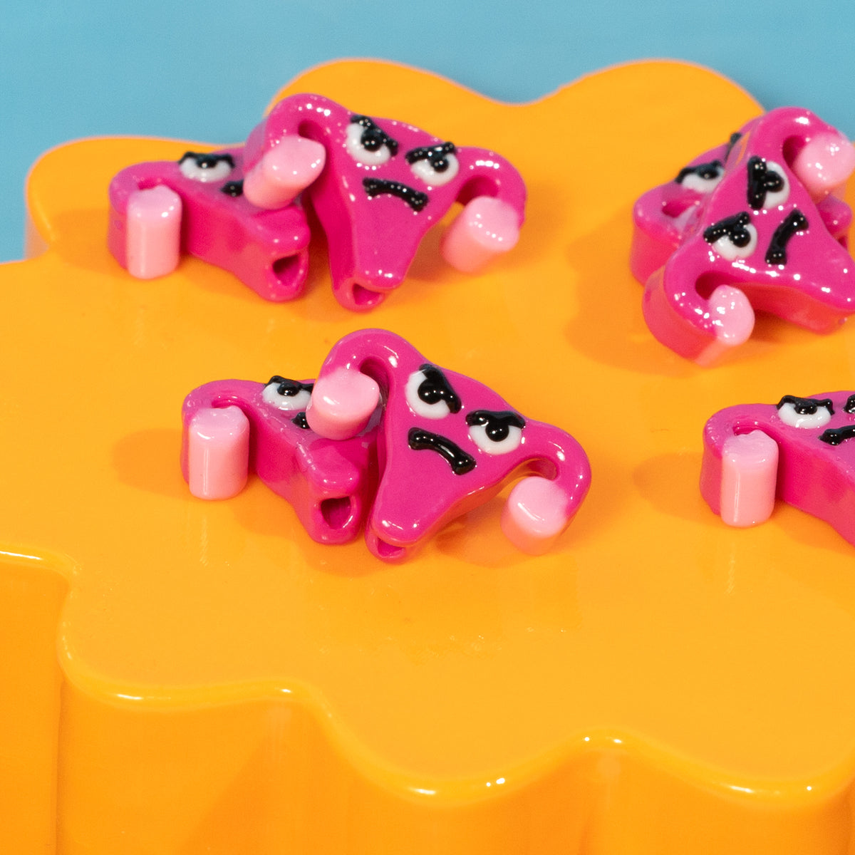 Close-up of scowling pink uterus kandi beads with light pink ovaries on an orange riser