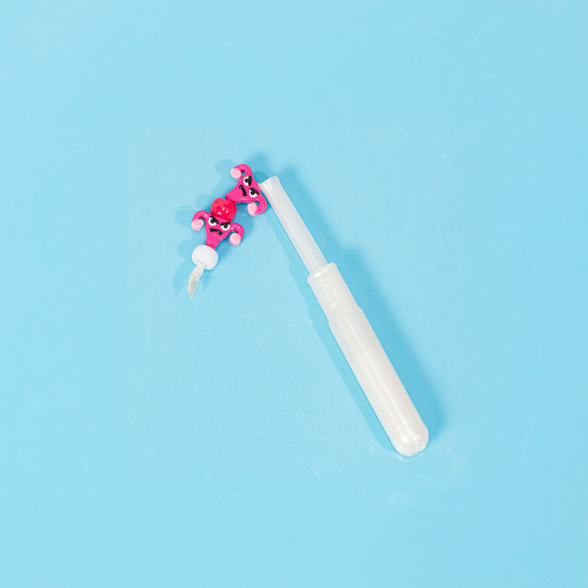 Two angry uterus kandi beads strung with red and white pony beads beside a tampon