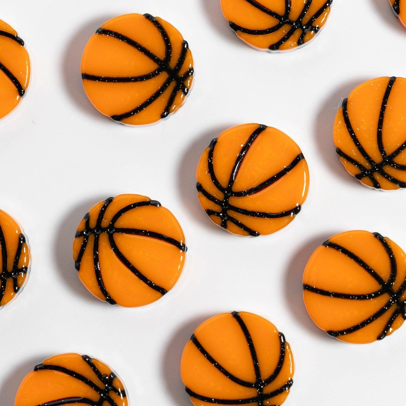 Orange basketball kandi beads with black seam lines laid out in diagonal rows on white, from above