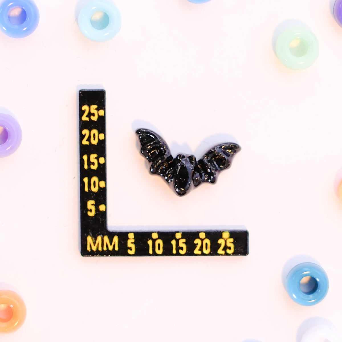 Size guide: a bat kandi bead beside a millimeter ruler for scale