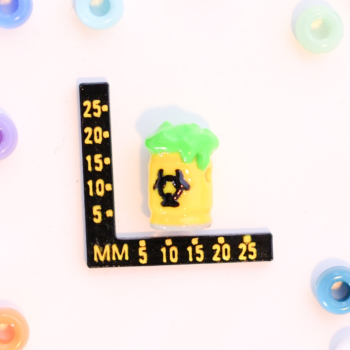 Size guide: a biohazard barrel kandi bead beside a millimeter ruler for scale