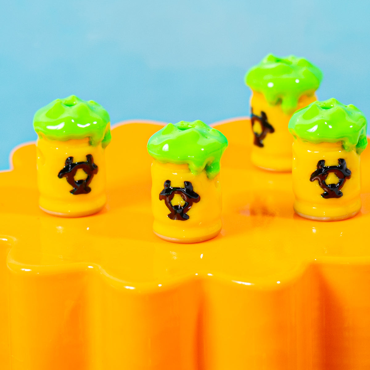 Yellow and green toxic barrel kandi beads lined up on an orange riser
