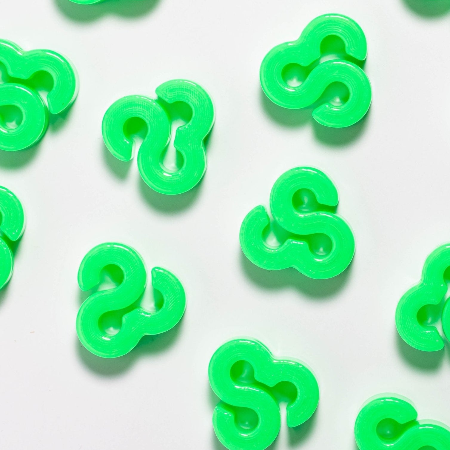 Neon green Bonnaroo loop kandi beads scattered across a white surface, seen from above