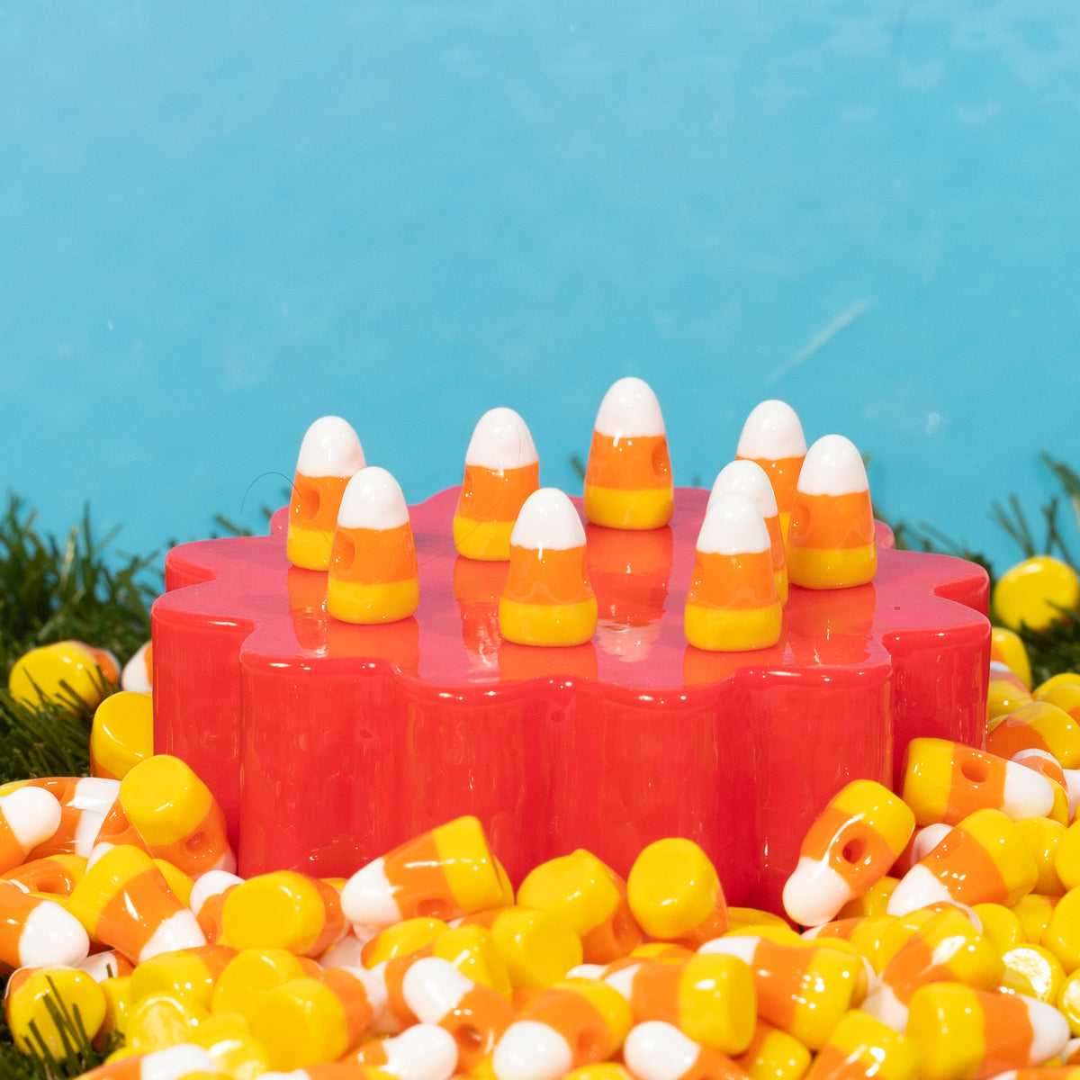 Candy corn kandi beads standing upright on a red riser, surrounded by a pile of more