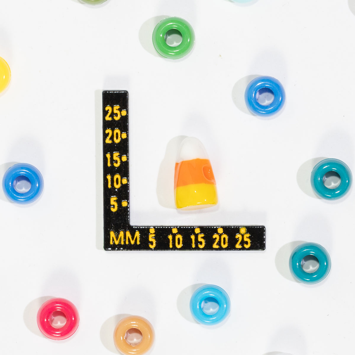 Size guide: a candy corn kandi bead beside a millimeter ruler for scale