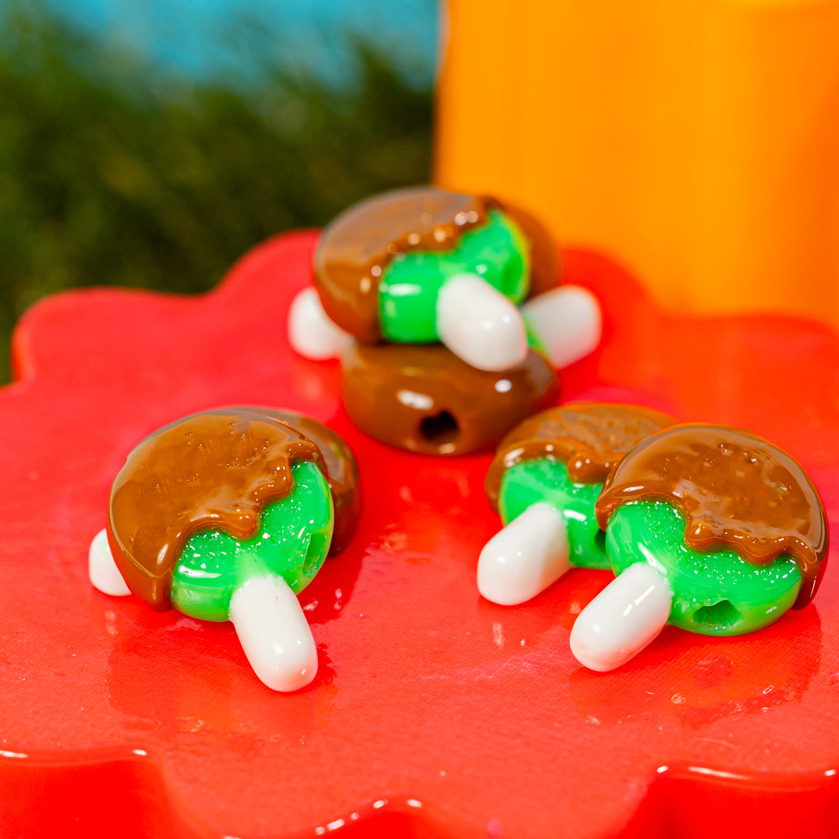 Caramel apple kandi beads piled on a red riser, drilled holes visible
