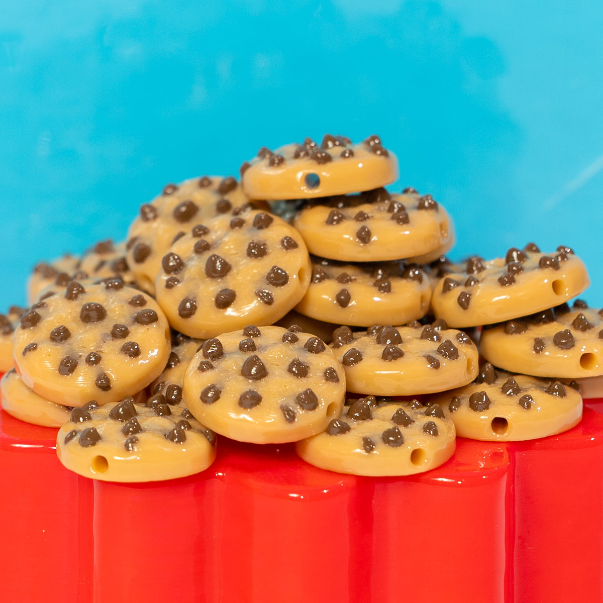 A pile of chocolate chip cookie kandi beads on a red riser, drilled holes visible