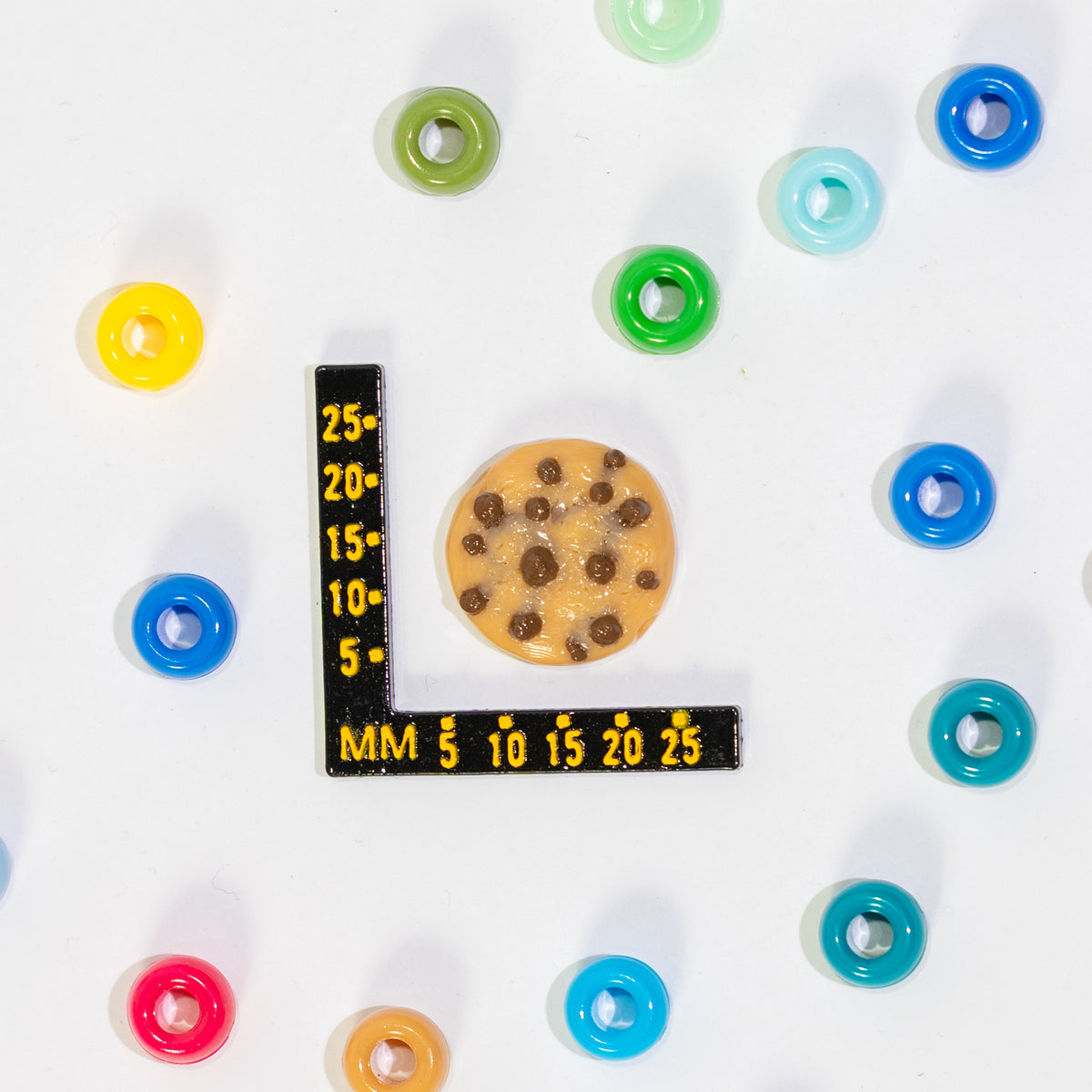 Size guide: a chocolate chip cookie kandi bead beside a millimeter ruler for scale