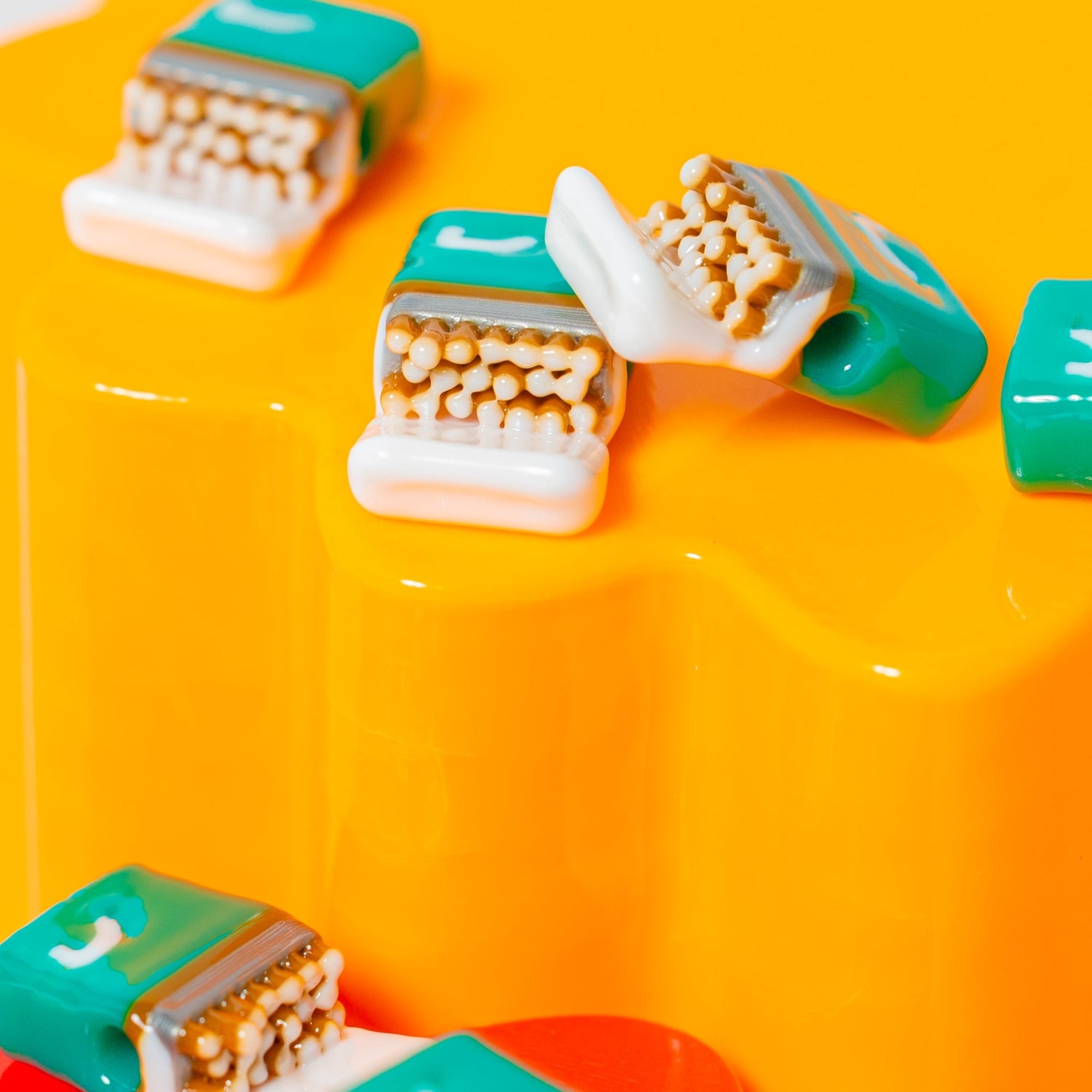 Open teal cigarette-pack kandi beads showing tan cigarettes, on a glossy yellow riser