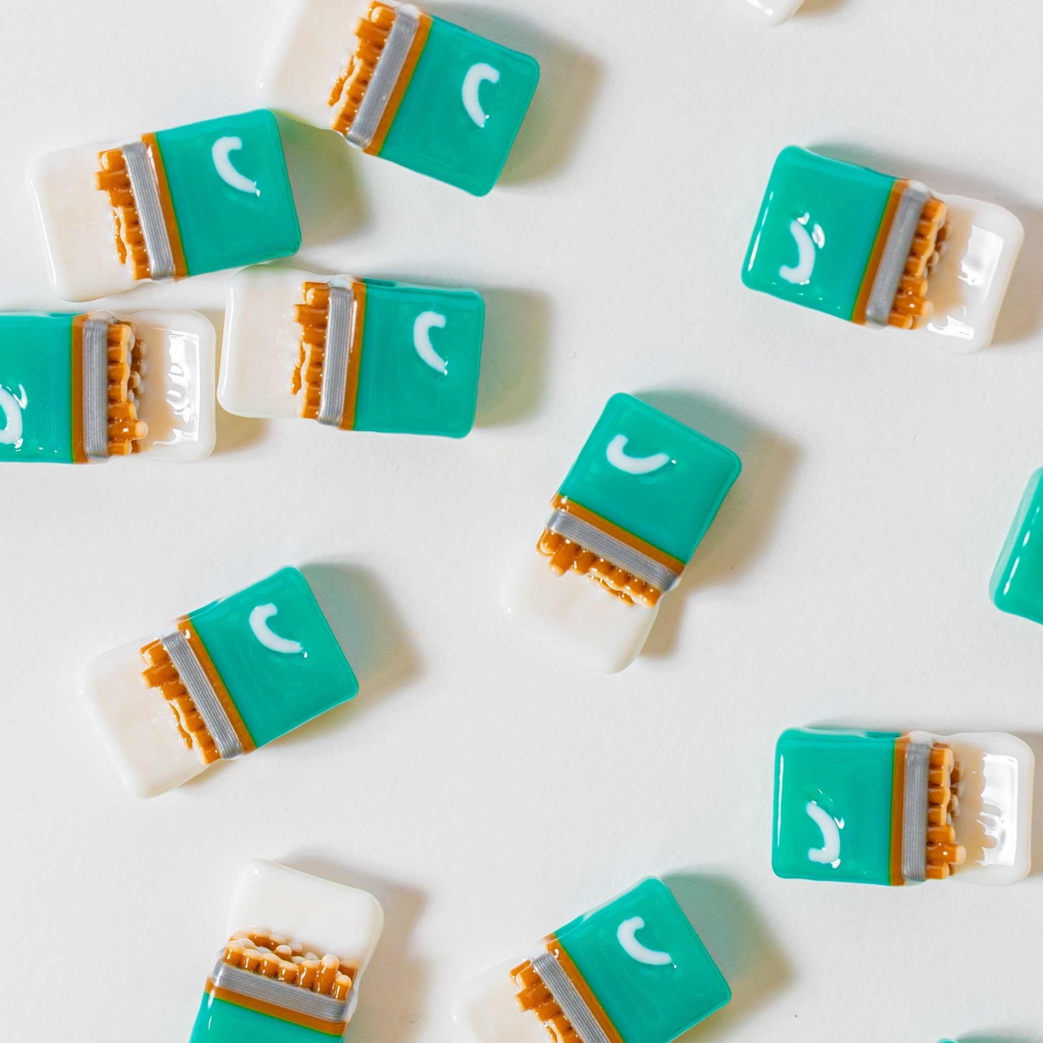 Teal and white cigarette-pack kandi beads spread across a white surface