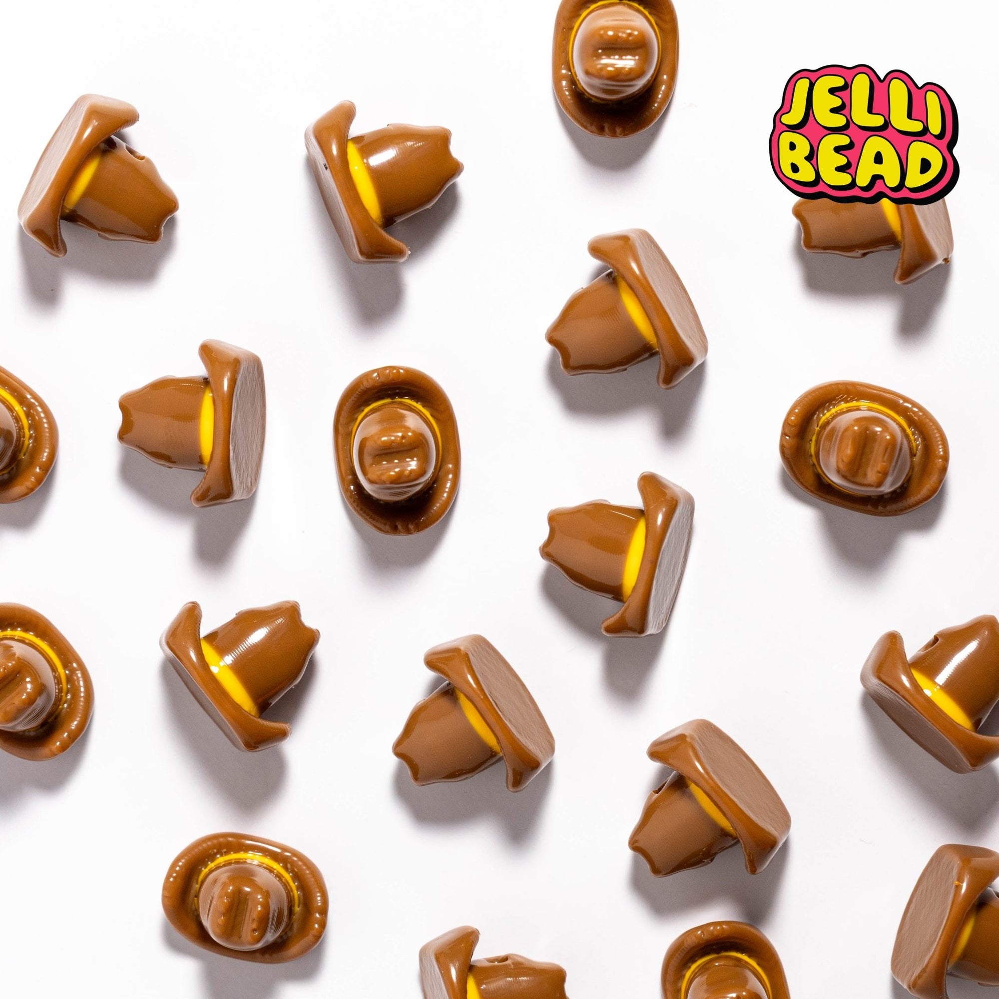 Brown cowboy hat beads with yellow bands scattered face-up and face-down on white