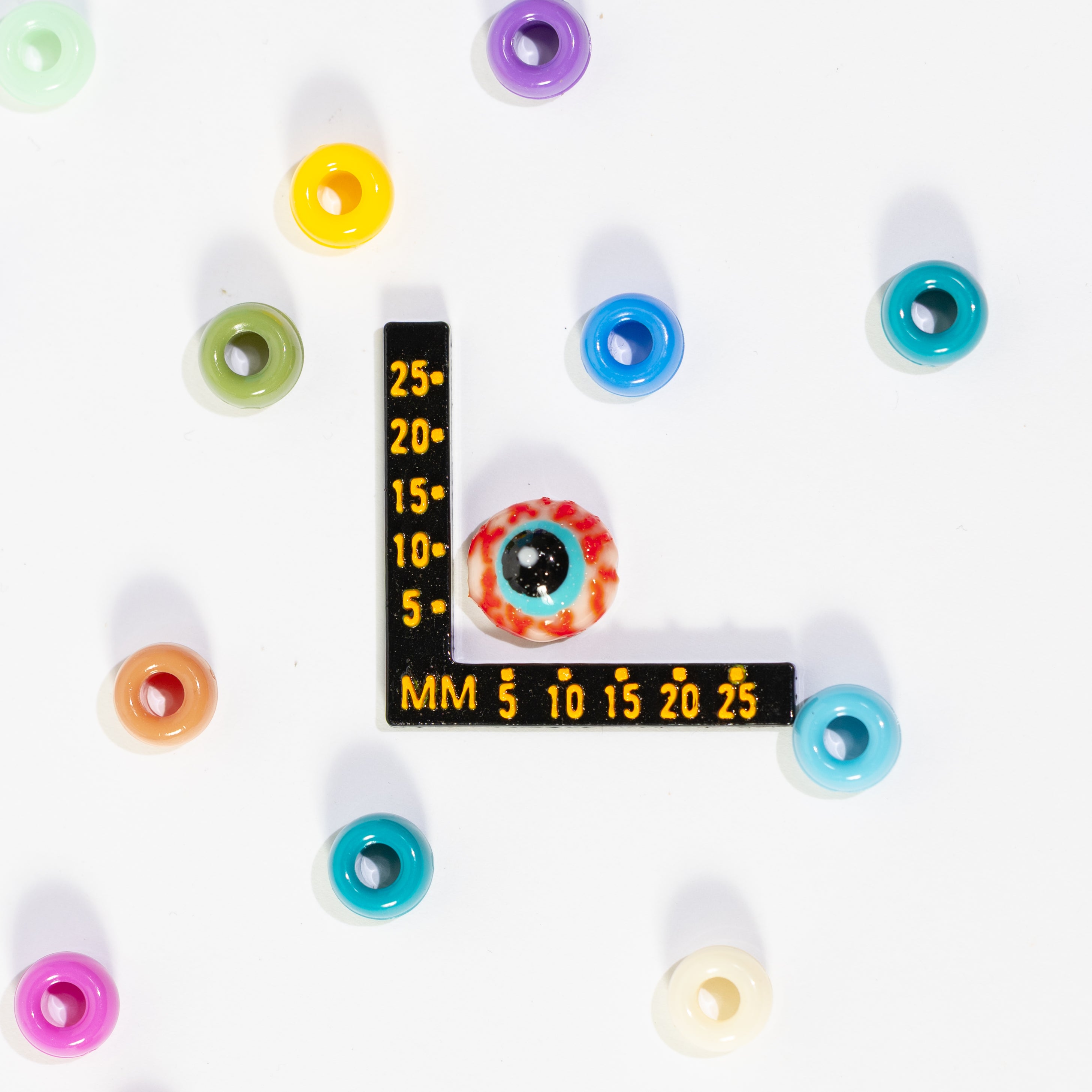 Size guide: an eyeball kandi bead beside a millimeter ruler for scale