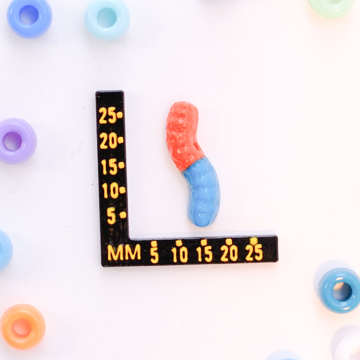 Size guide: a gummy worm kandi bead beside a millimeter ruler for scale