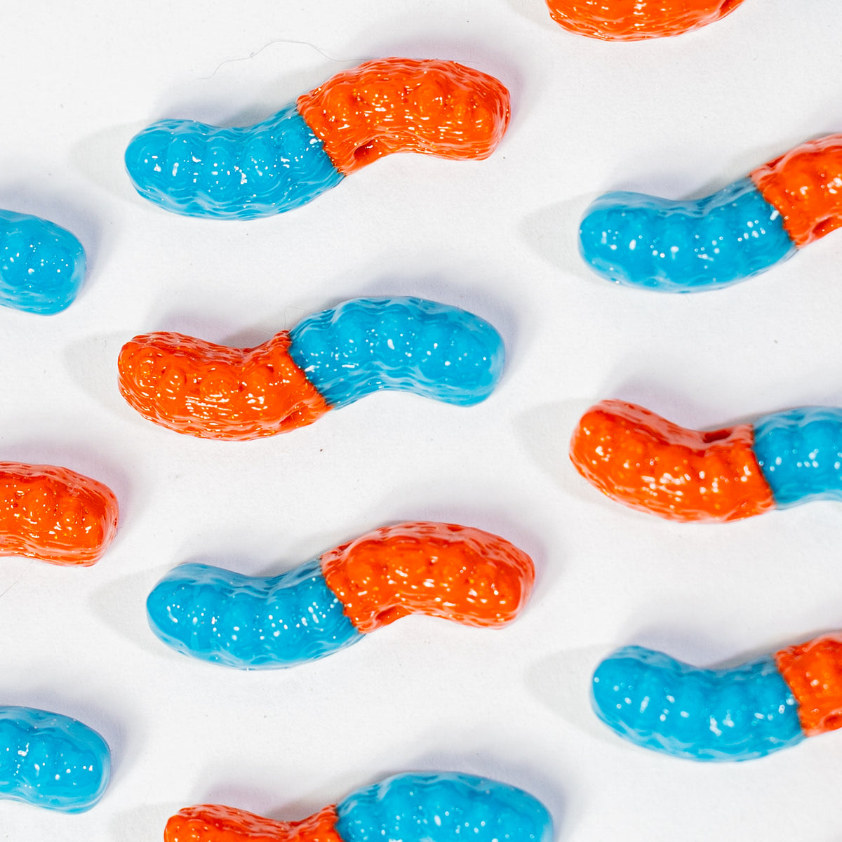 Rows of two-tone gummy worm kandi beads on a white background
