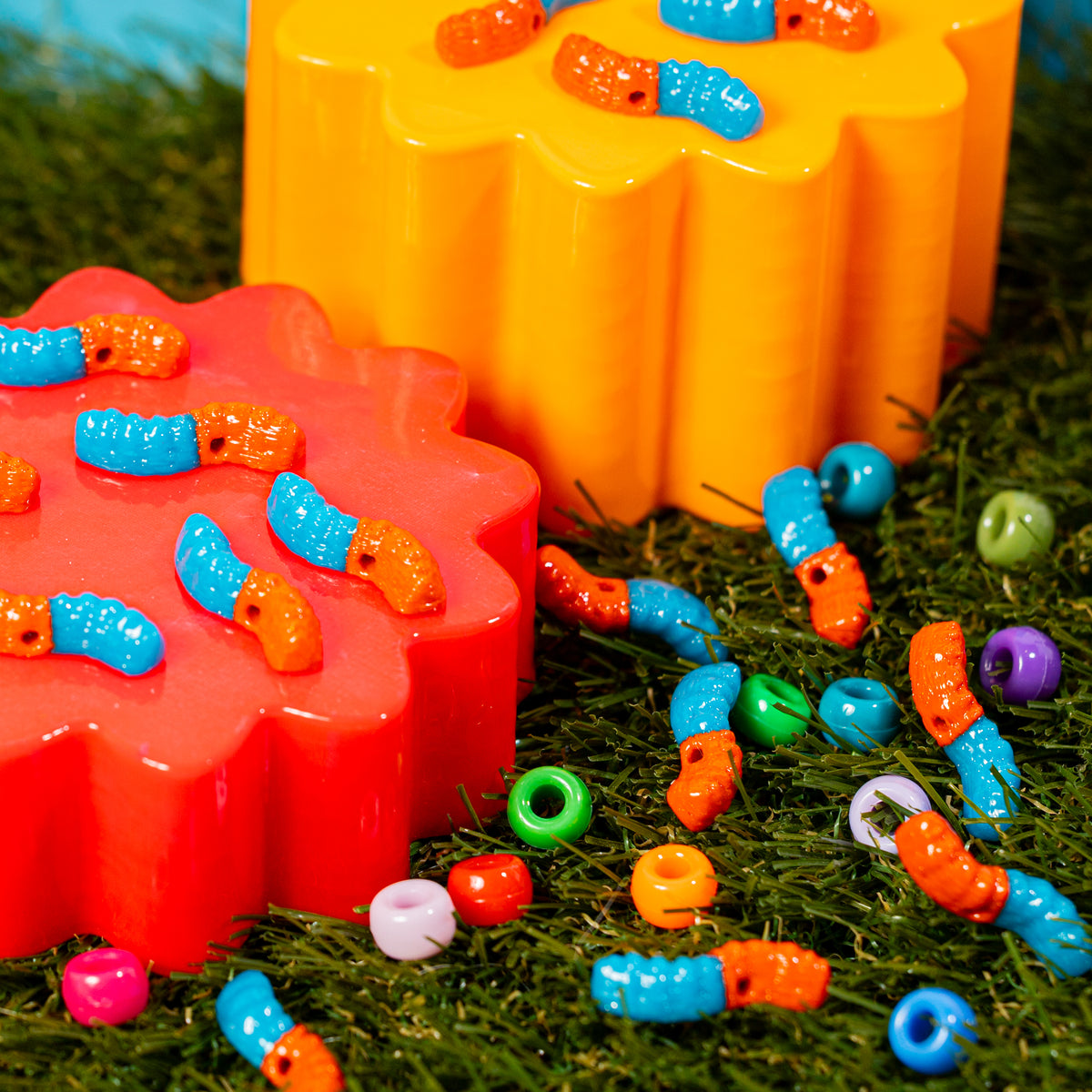 Gummy worm kandi beads crawling over red and orange risers into green grass