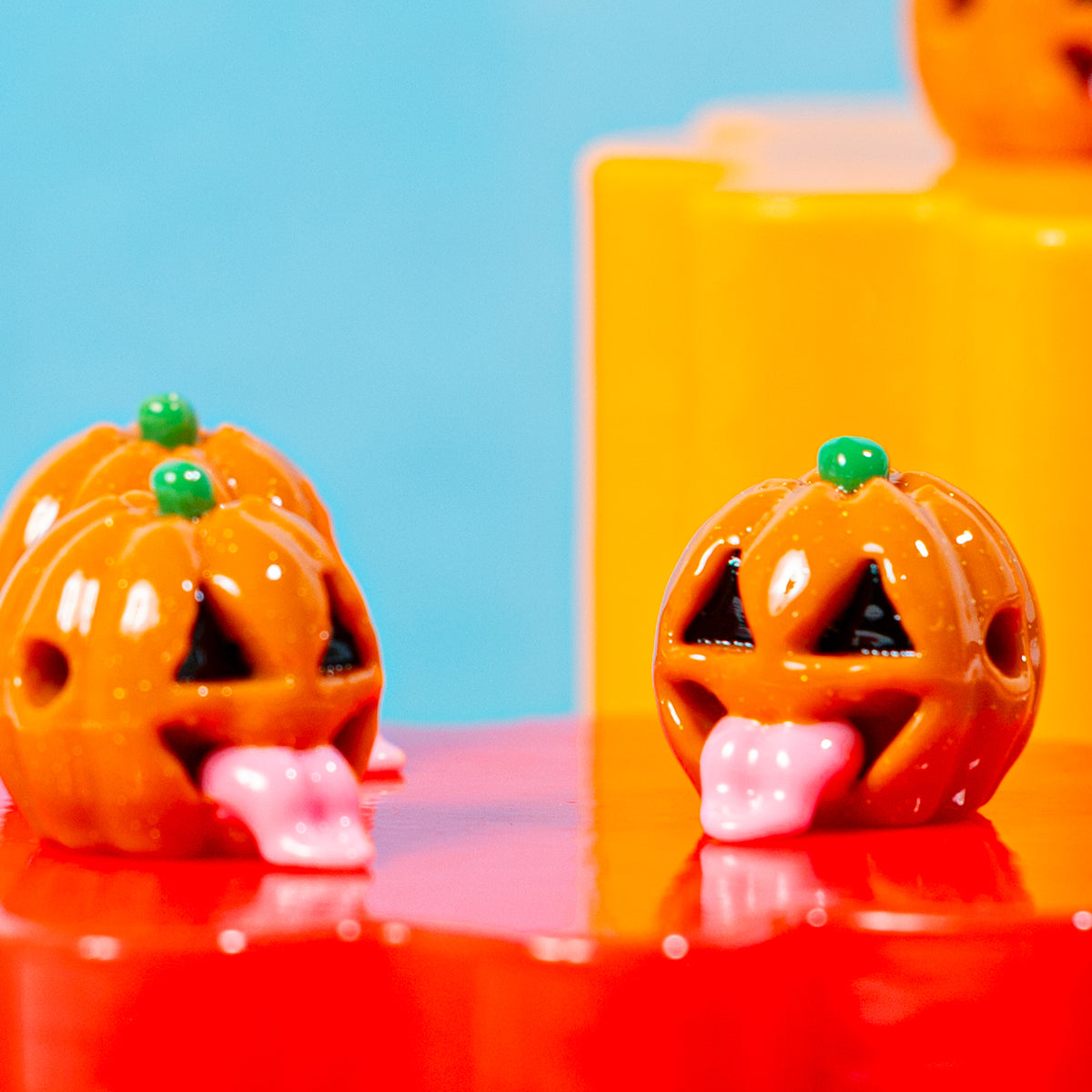 Jack o lantern kandi beads on red and orange risers against a blue backdrop