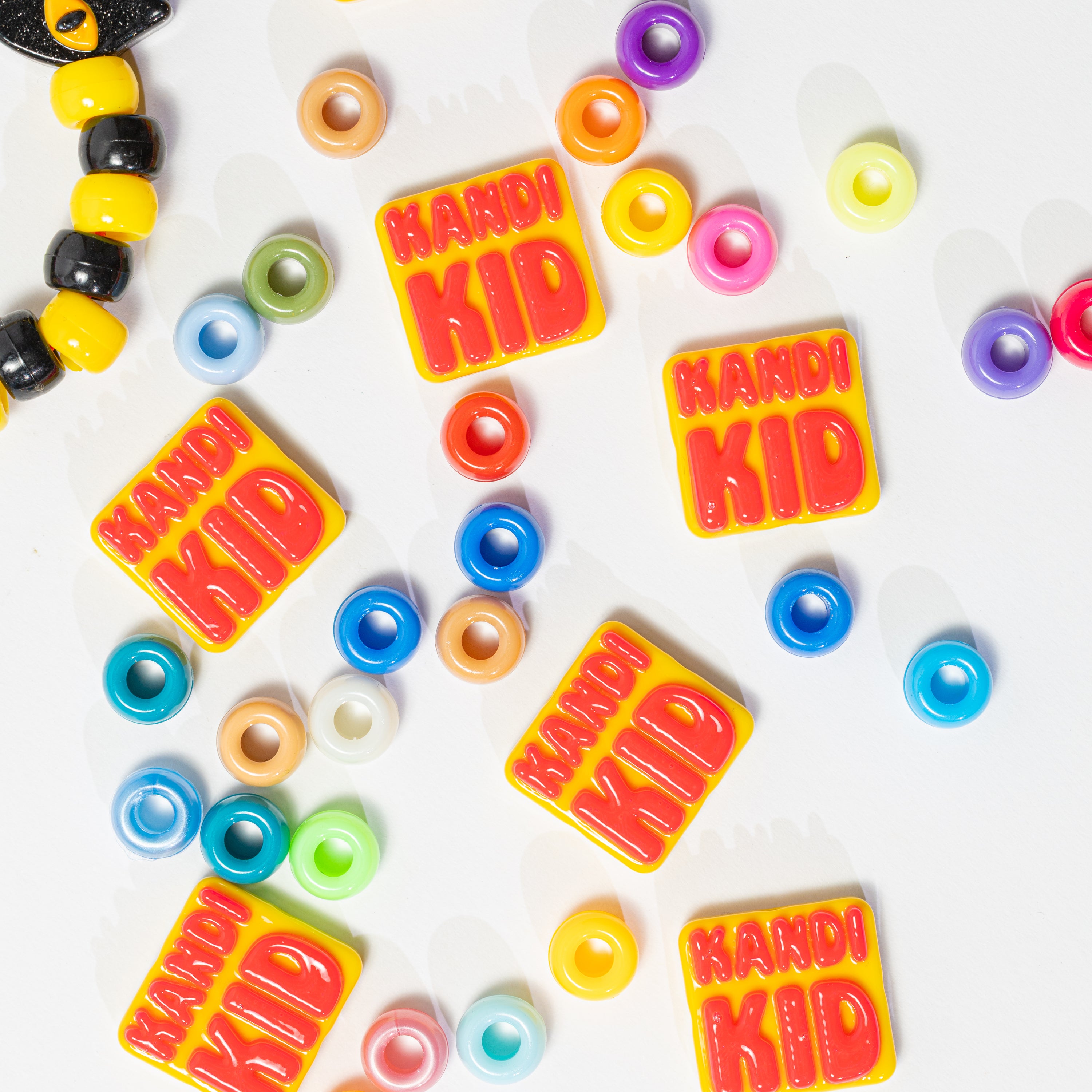KANDI KID kandi beads scattered on white with rainbow pony beads and a kandi bracelet