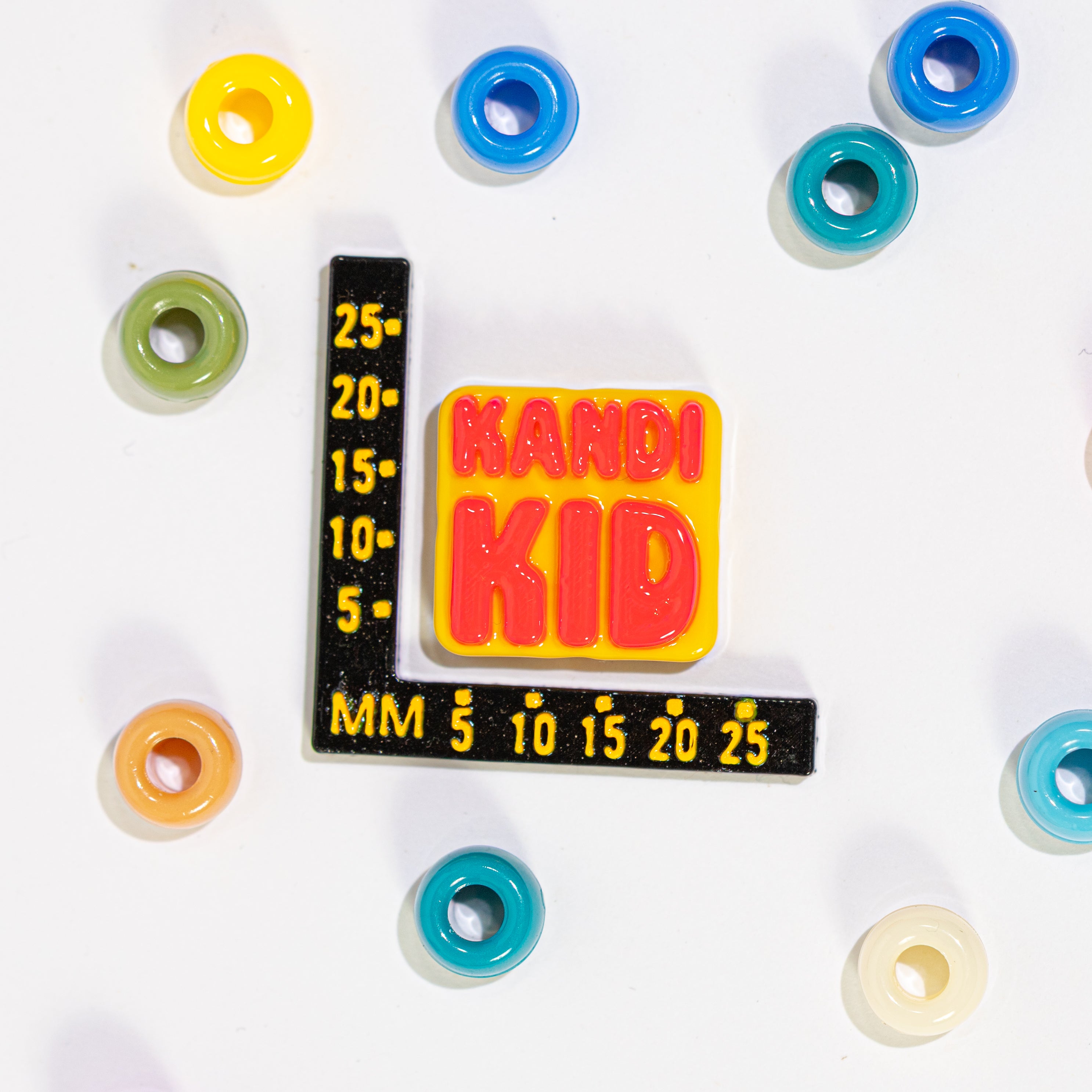 Size guide: a KANDI KID kandi bead beside a millimeter ruler for scale