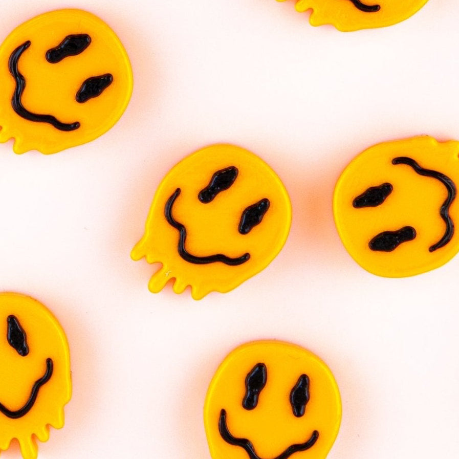 Melted smiley beads for kandi bracelets laid out in an even scattered grid, from above