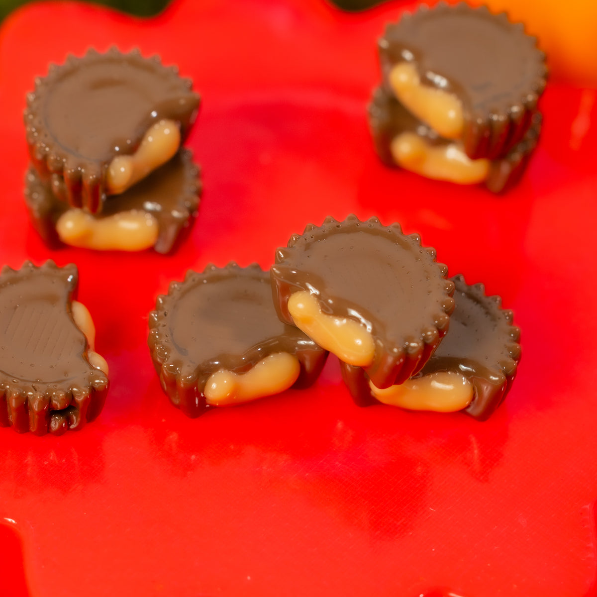 Stacks of bitten peanut butter cup kandi beads on a glossy red riser