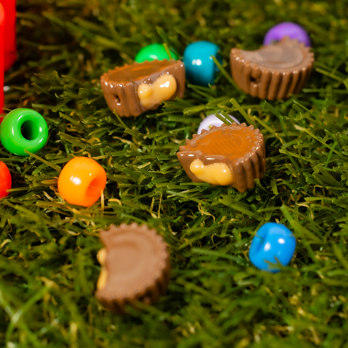 Chocolate and peanut butter kandi beads scattered in green grass with colorful beads