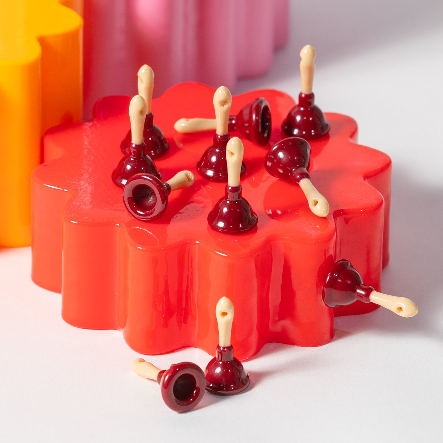 Dark red plunger kandi beads with cream handles standing upright on a red riser
