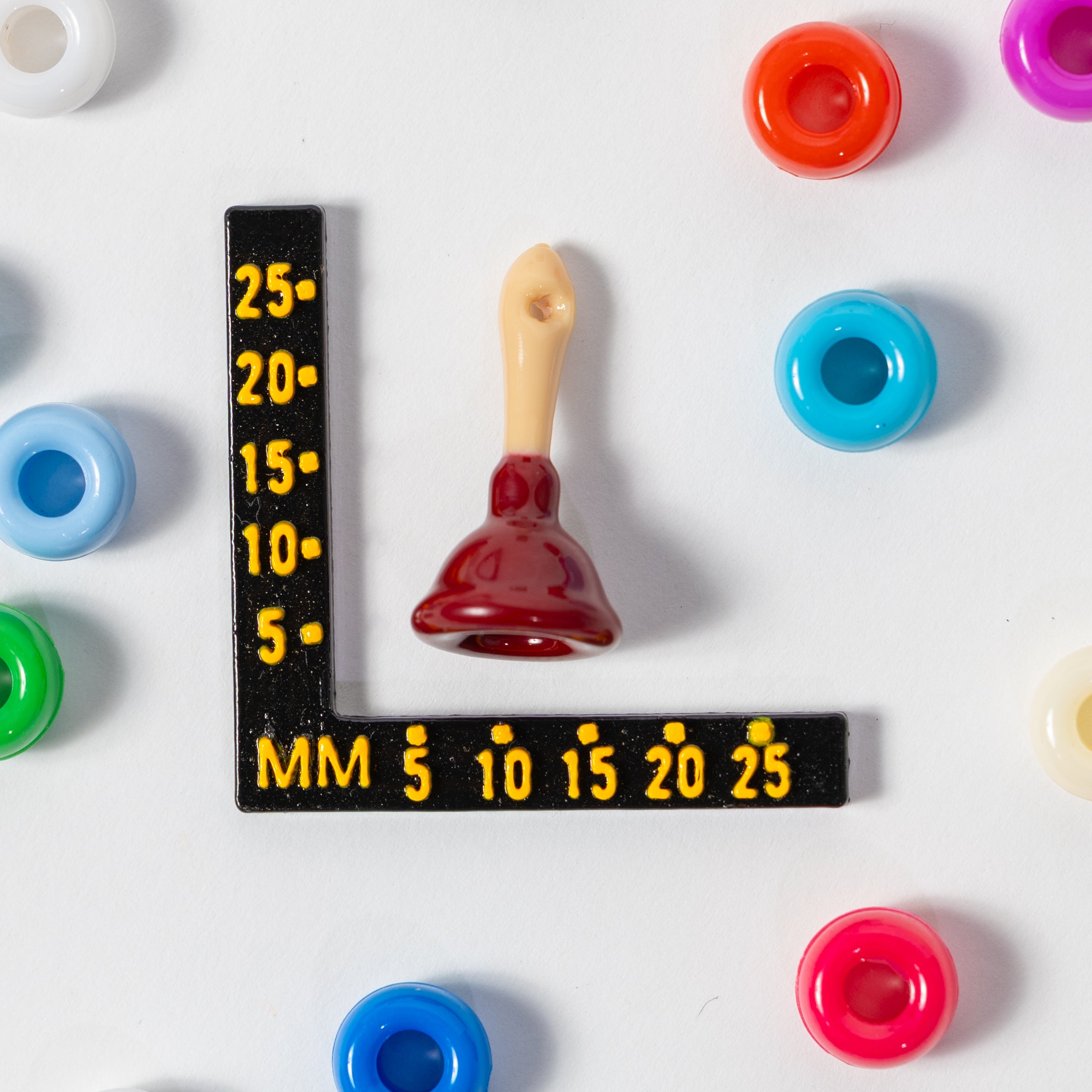 Size guide: a plunger kandi bead beside a millimeter ruler for scale