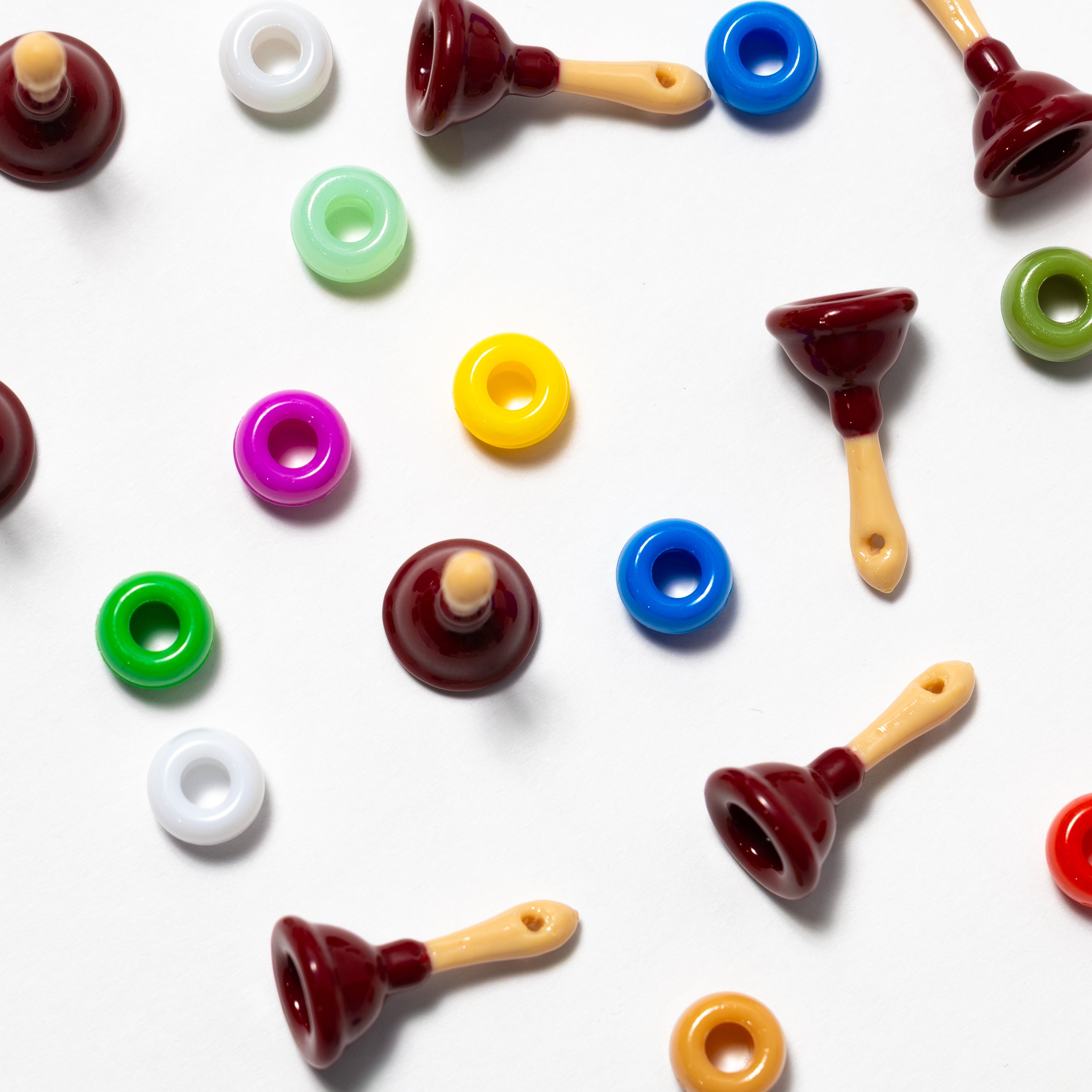 Plunger kandi beads mixed with rainbow pony beads across a white background