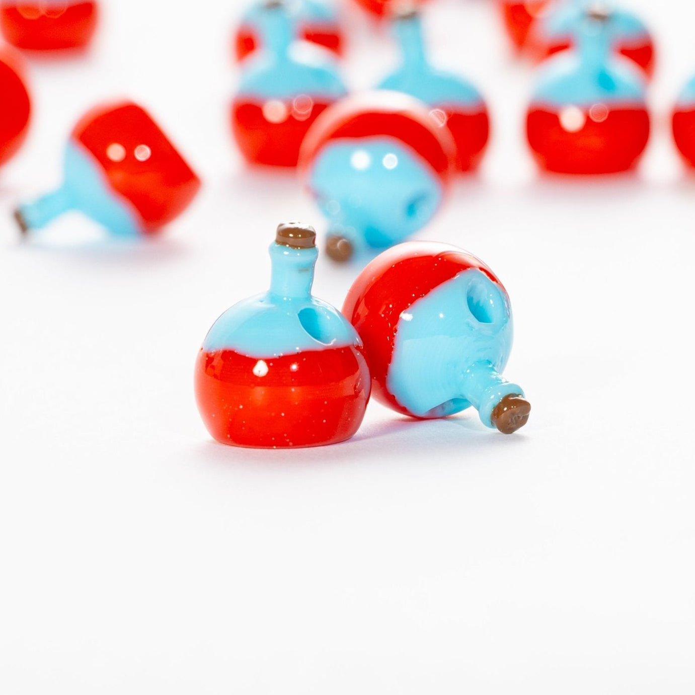 Red and blue potion bottle kandi beads, one upright and one on its side showing the hole