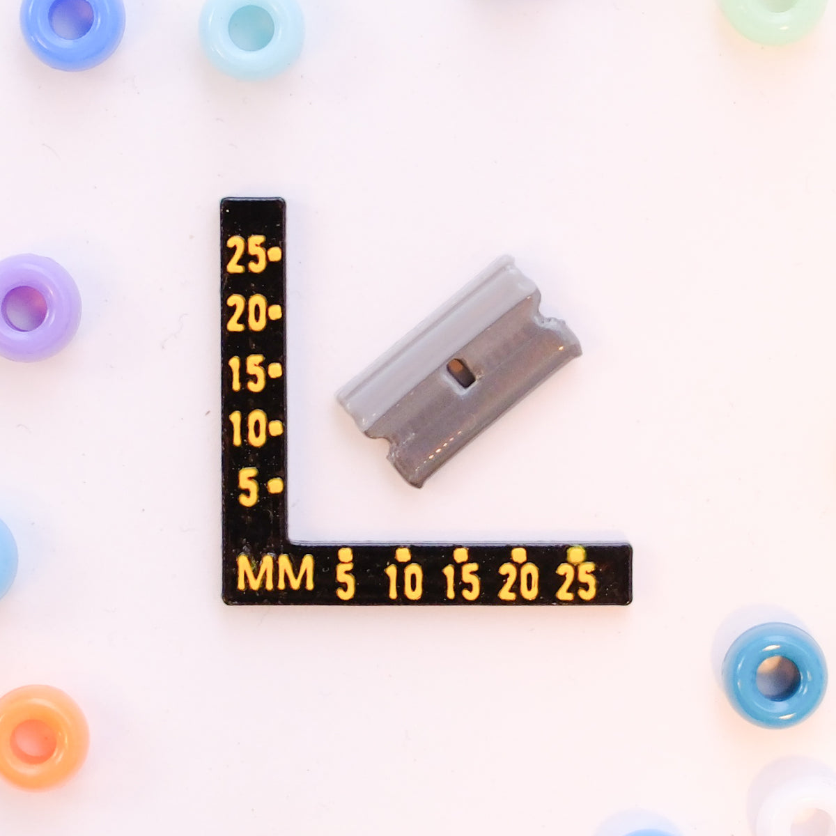 Size guide: a razor blade kandi bead beside a millimeter ruler for scale