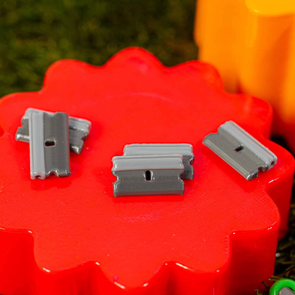 Razor blade kandi beads lying on a glossy red riser