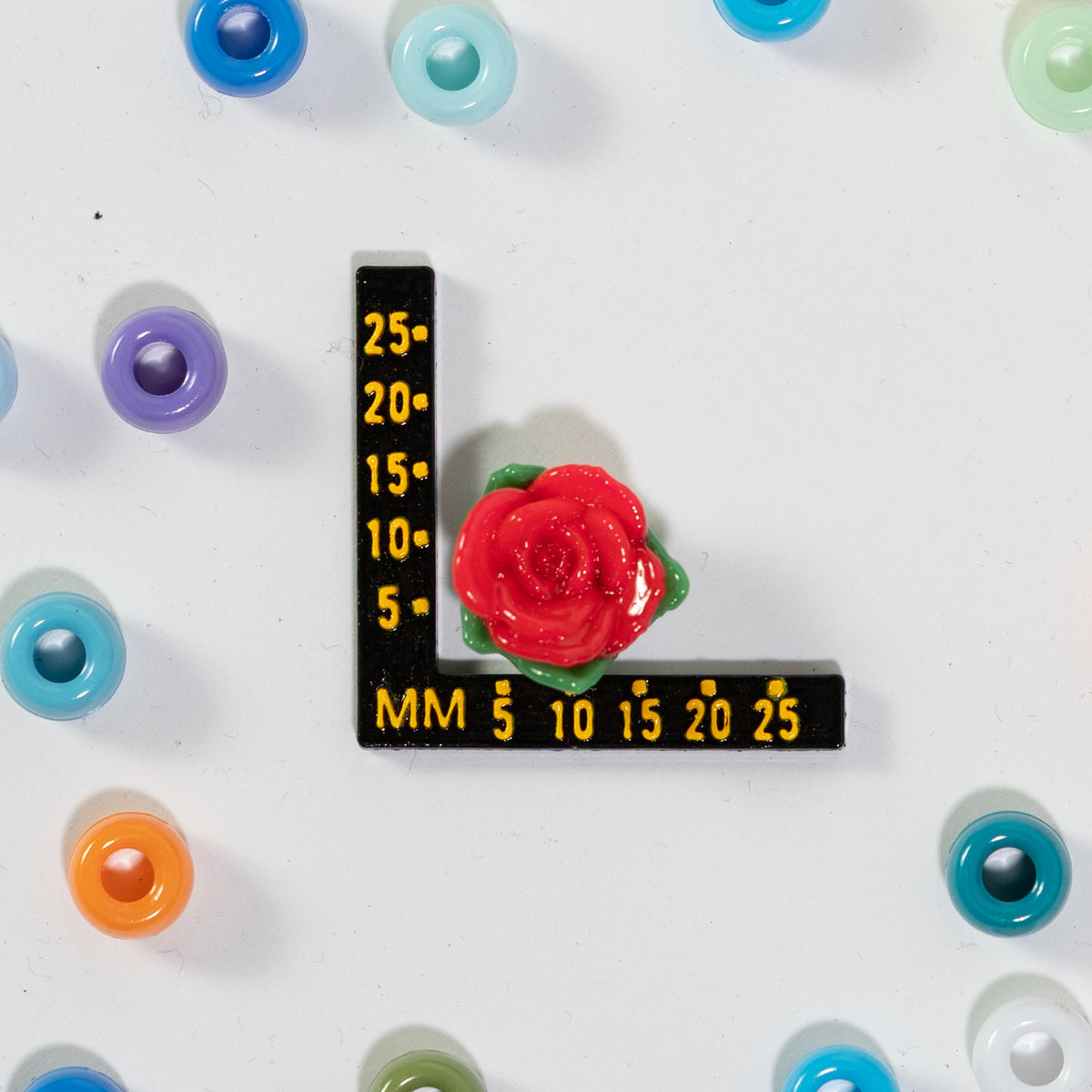 Size guide: a red rose kandi bead beside a millimeter ruler, 18mm across
