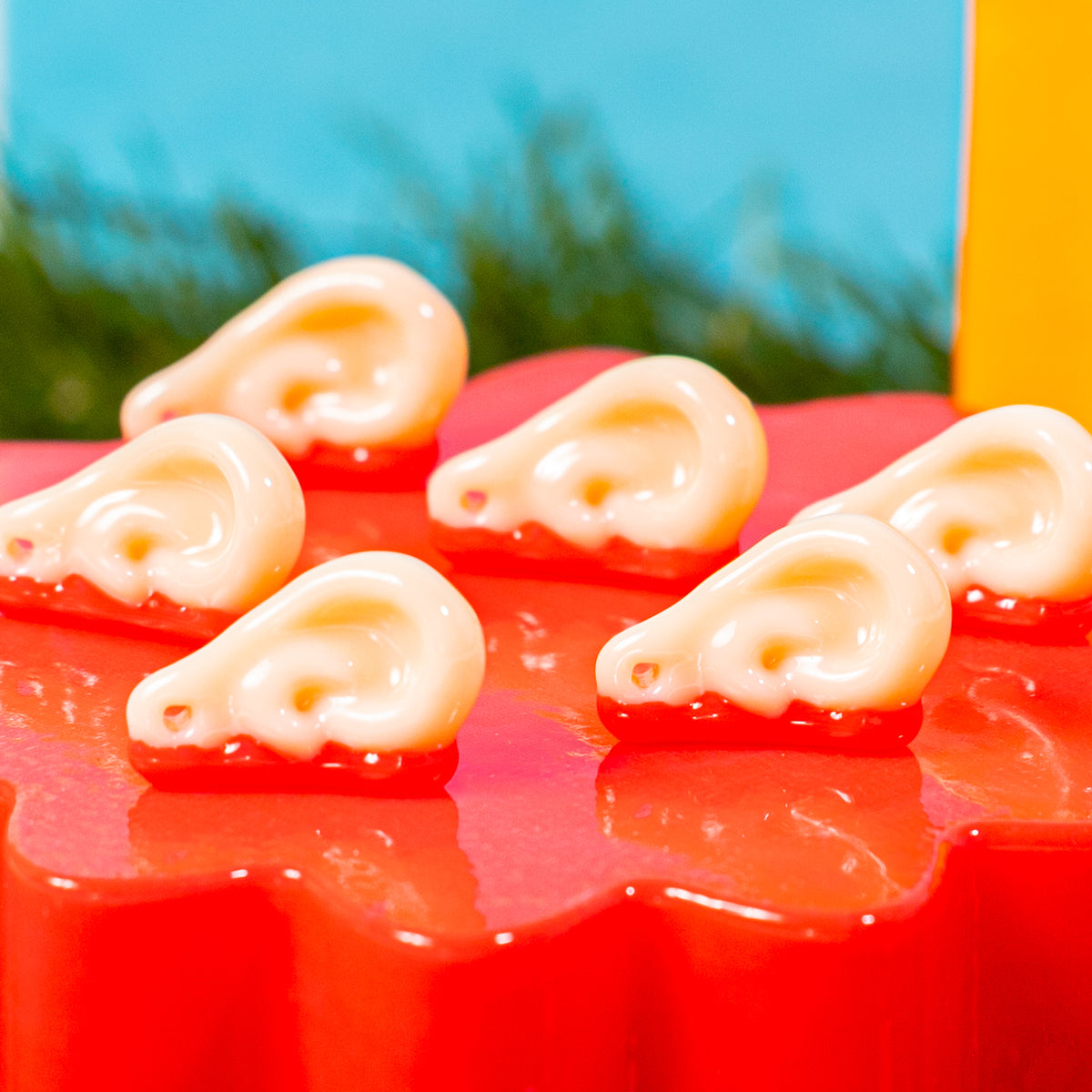 Close-up of severed ear kandi beads with bloody red edges on a red riser