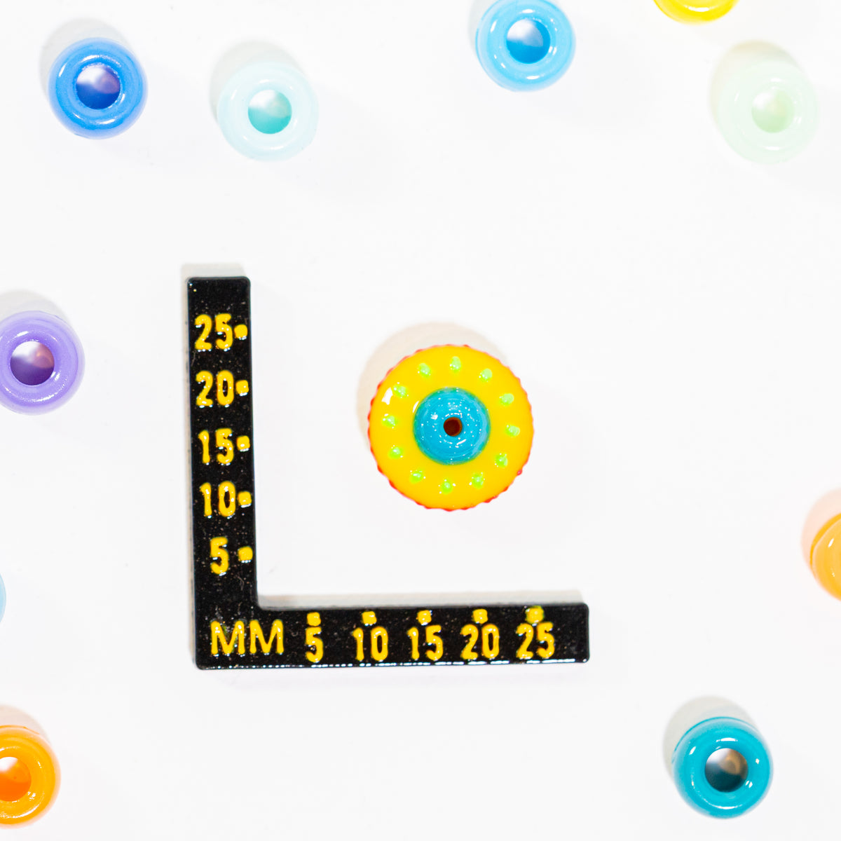 Size guide: a spaceship kandi bead beside a millimeter ruler for scale, top hole visible