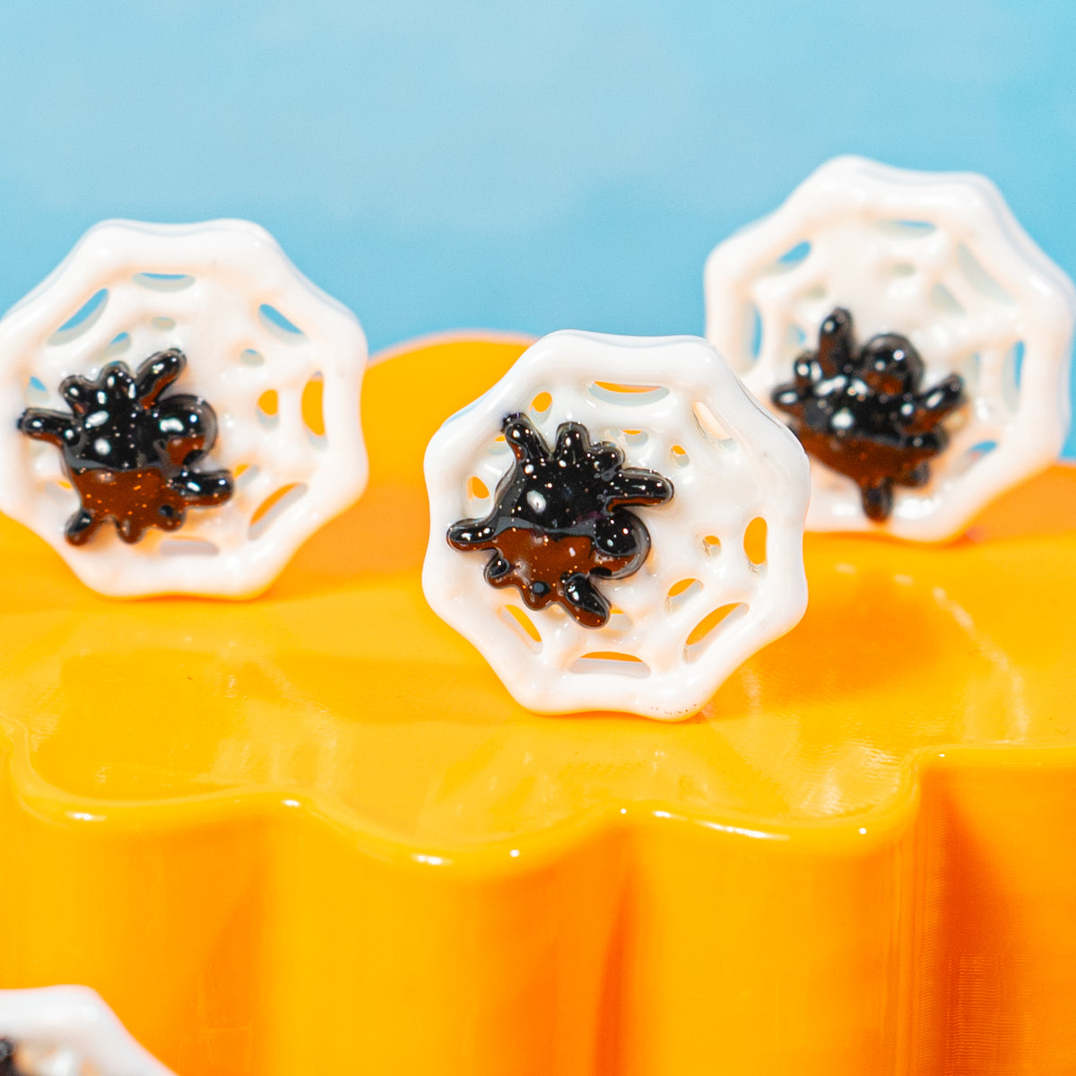 Close-up of white spider web kandi beads with black spiders on an orange riser