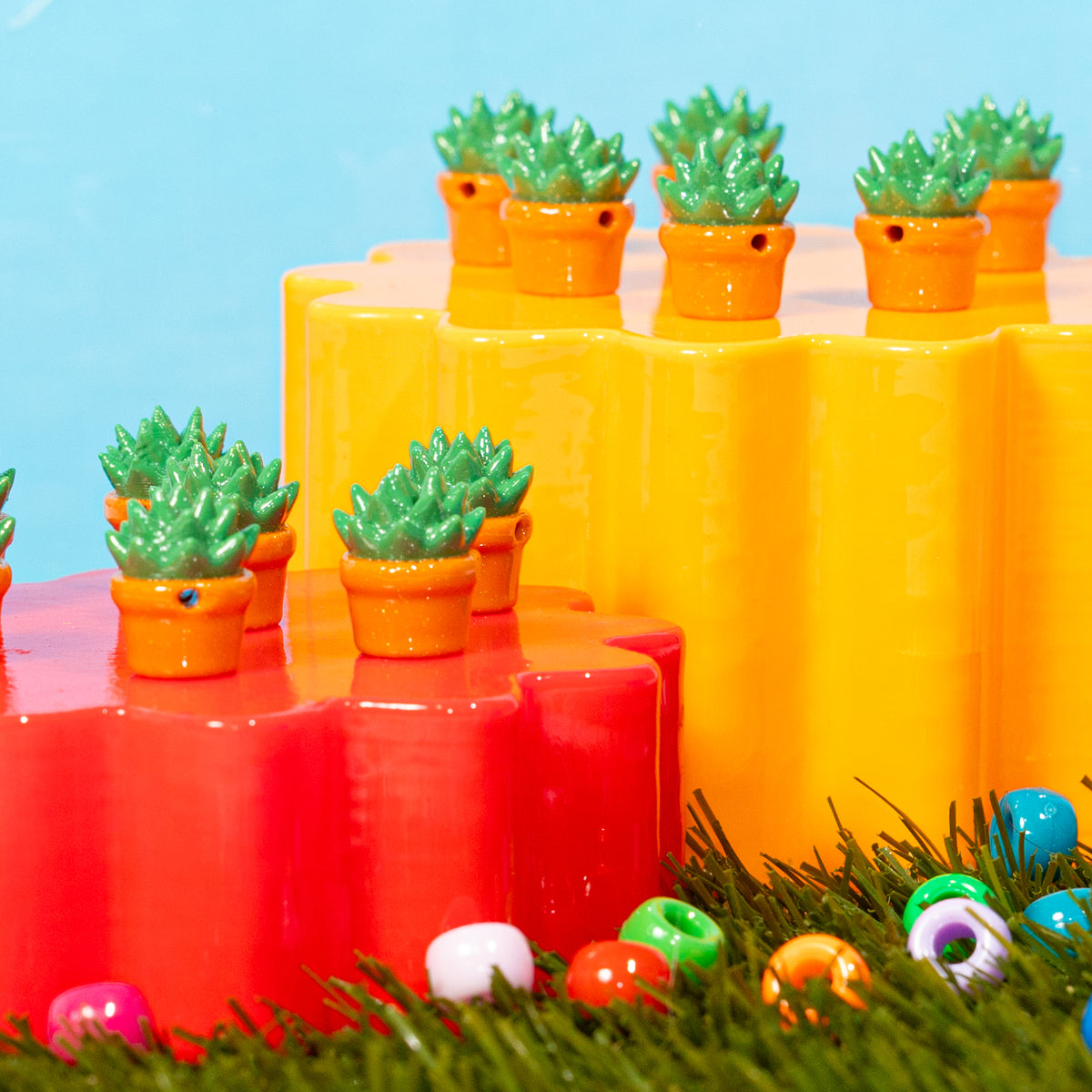 Potted succulent kandi beads on red and yellow risers with pony beads in the grass