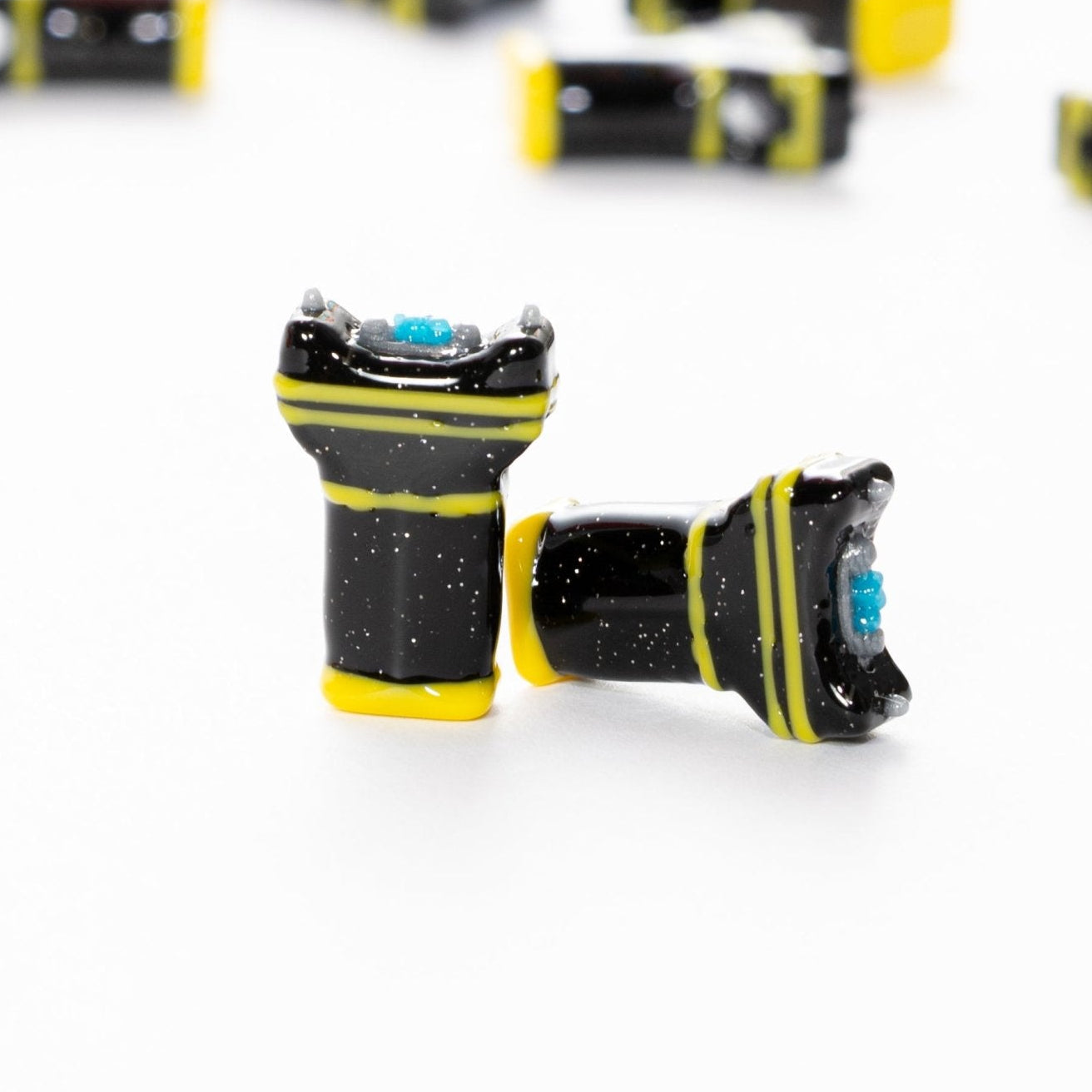 Two black and yellow taser kandi beads close up, one upright and one on its side