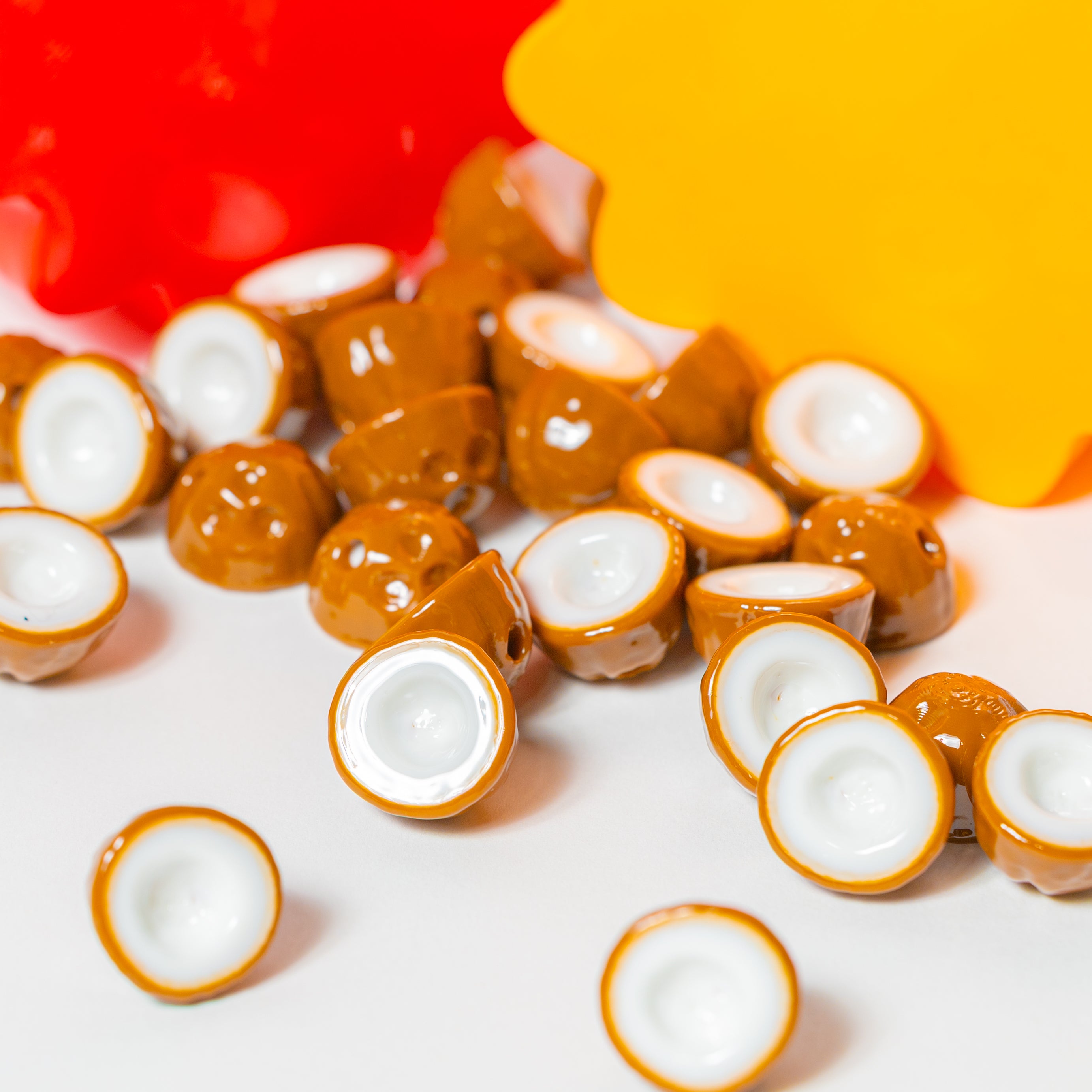 Brown coconut beads for kandi bracelets spilling on white with red and yellow flower risers behind