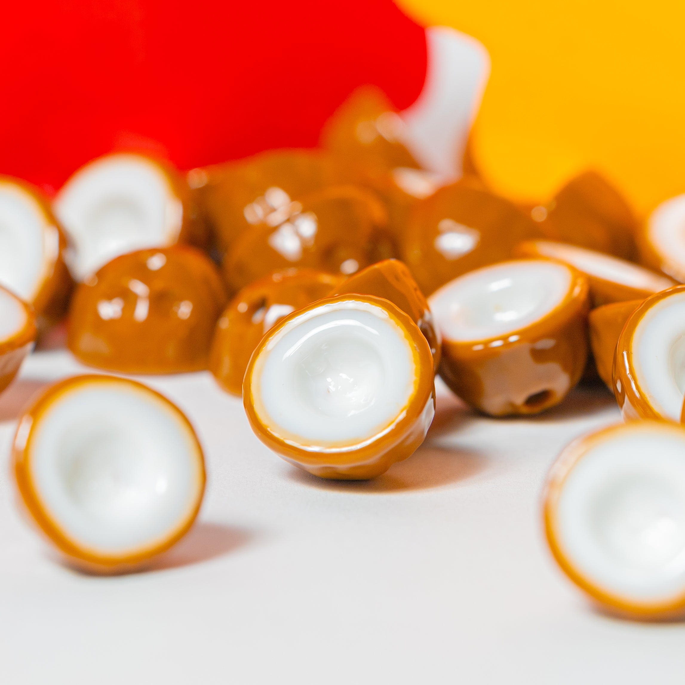 Close-up cluster of coconut kandi beads showing white flesh and brown husk, red and yellow behind