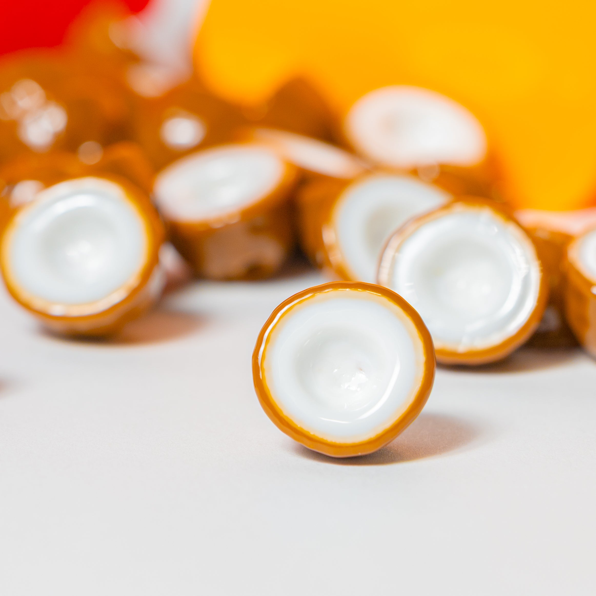 Close-up of brown coconut kandi beads with white flesh centers, one sharp in front, warm colors blurred behind