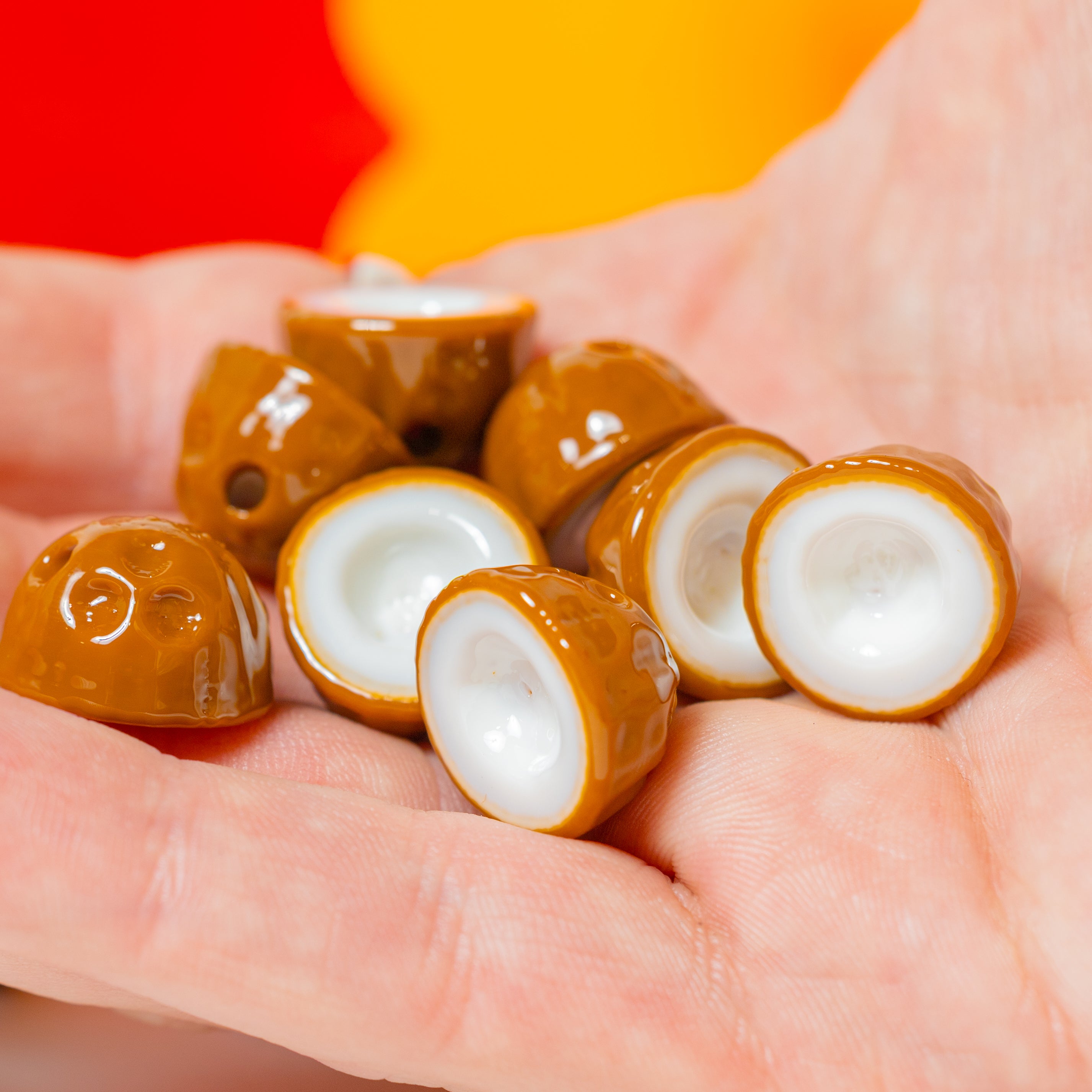Coconut kandi beads cupped in a palm, some showing the three-eyed brown husk, red and yellow behind