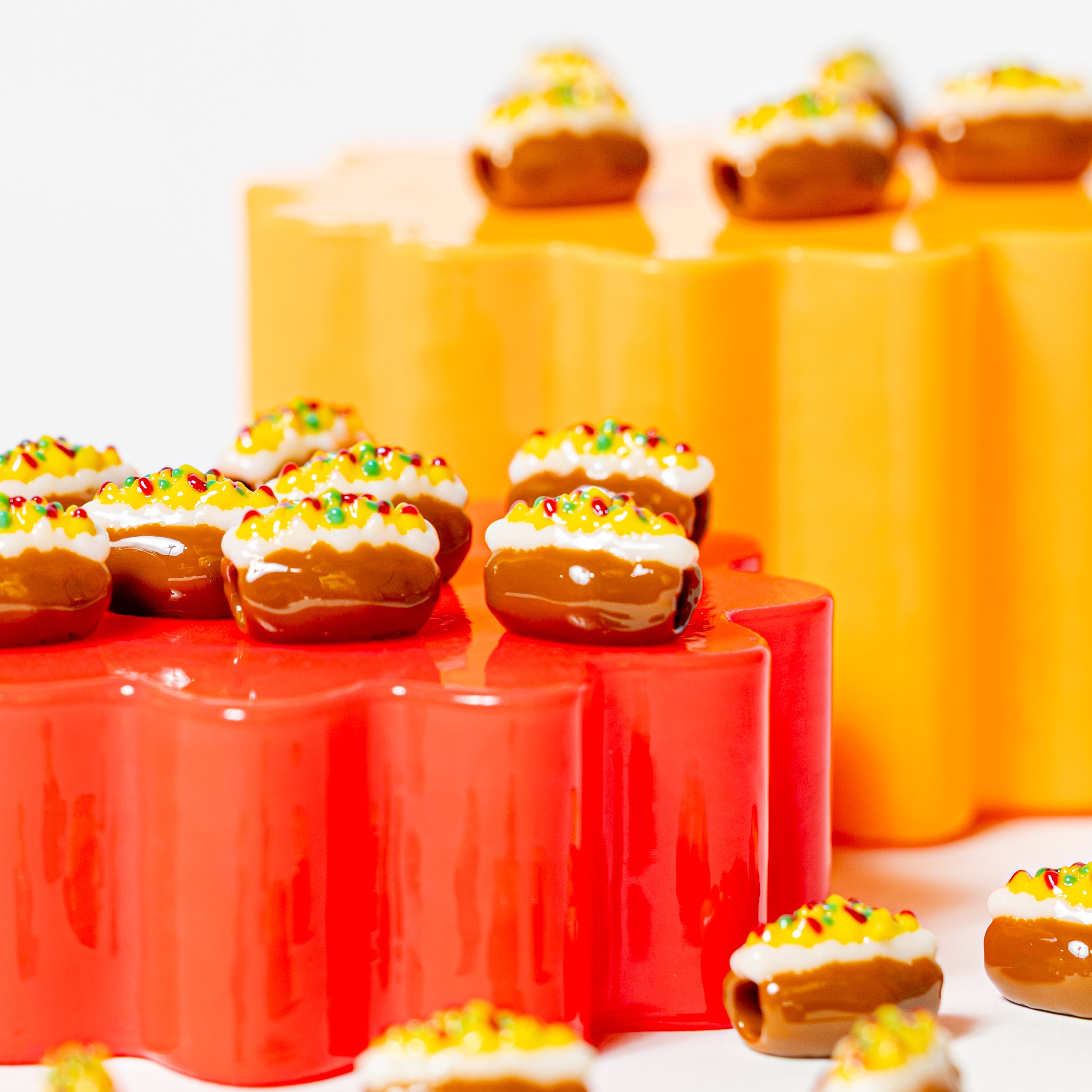 Loaded baked potato beads for kandi bracelets on stacked red and orange flower risers, white backdrop