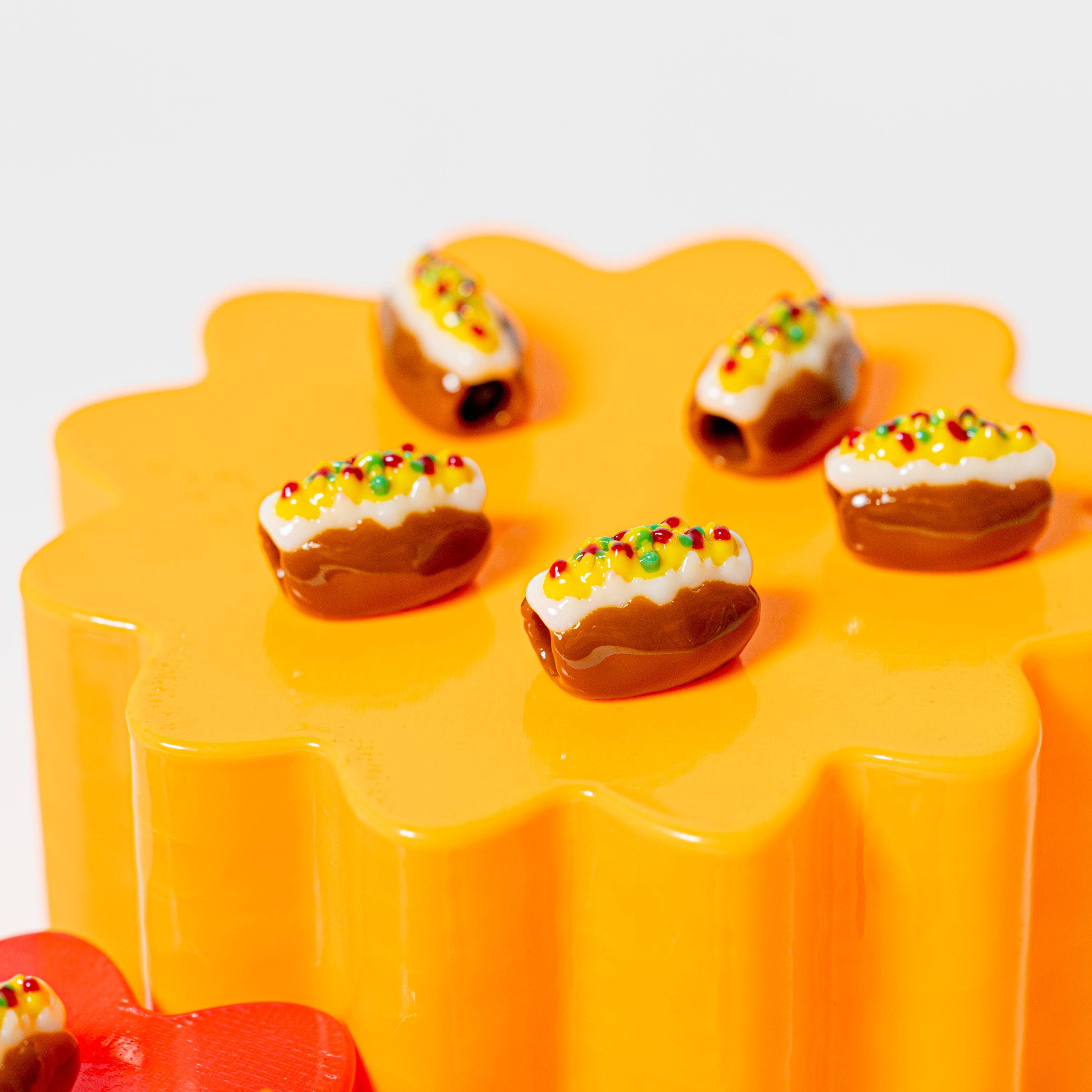 Loaded baked potato kandi beads topped with sour cream, cheese, bacon and chives on a glossy orange flower riser