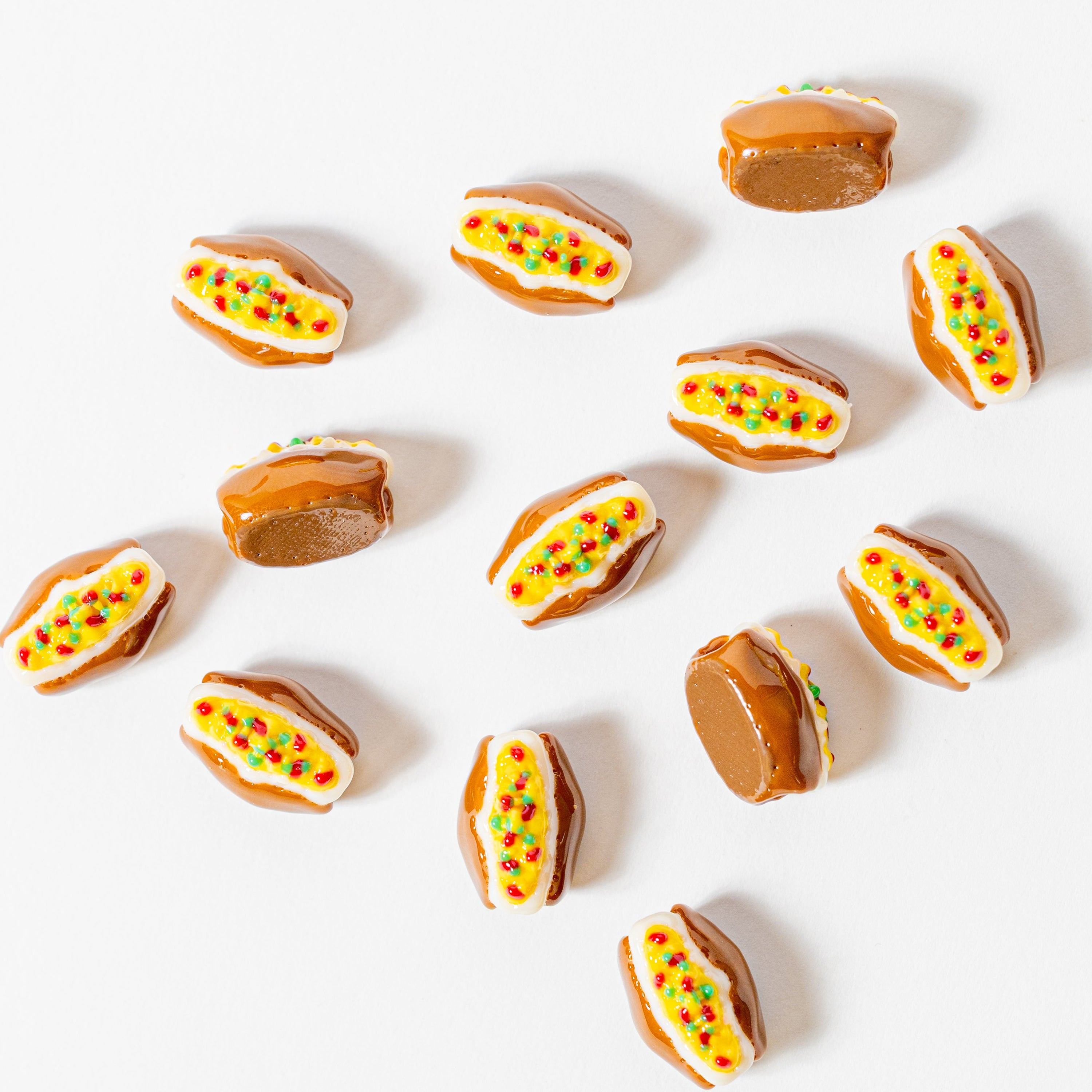 Baked potato kandi beads scattered every direction on white, some face-down showing drilled holes, from above