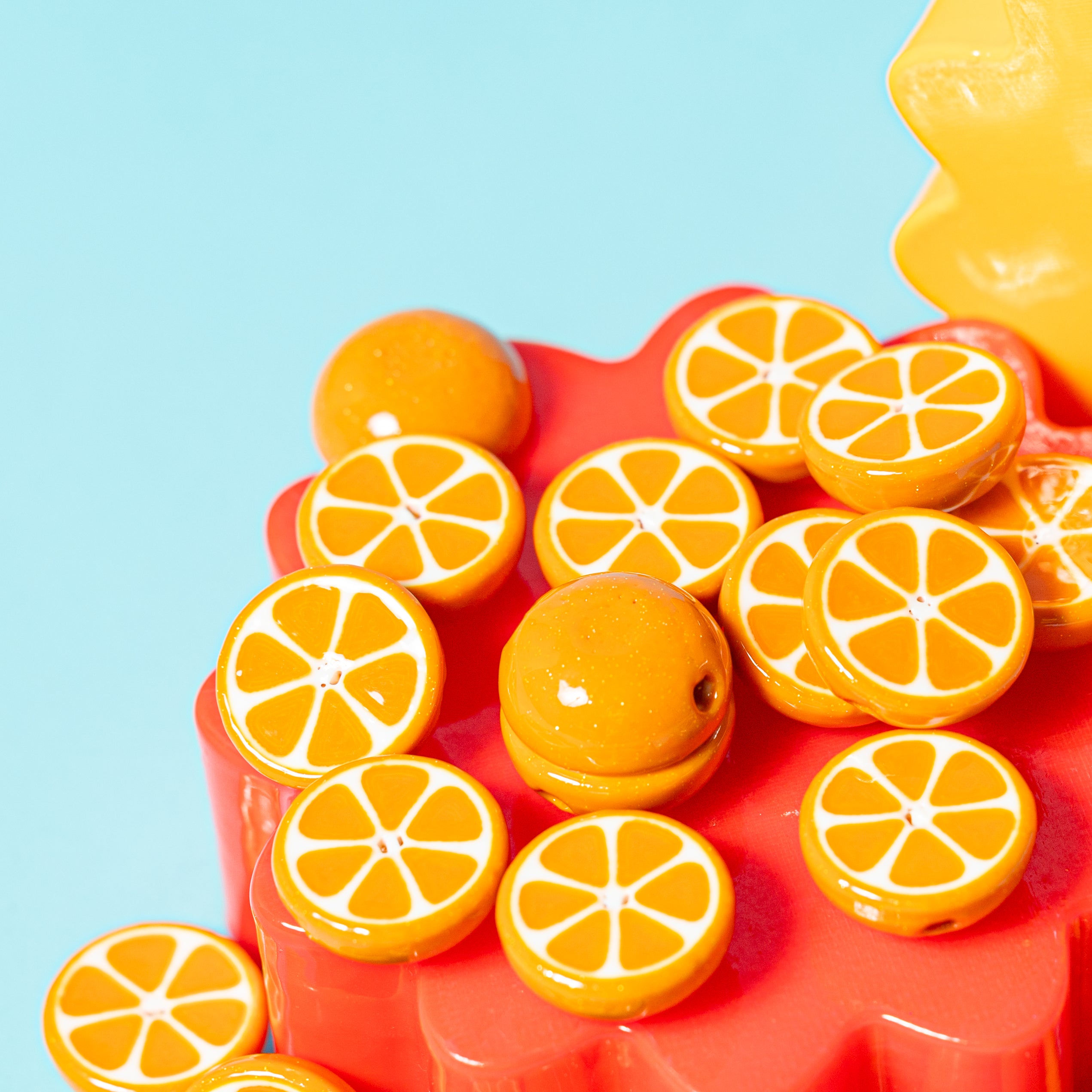 Close-up of orange slice kandi beads on a red riser, one whole-orange dome in the center, yellow behind