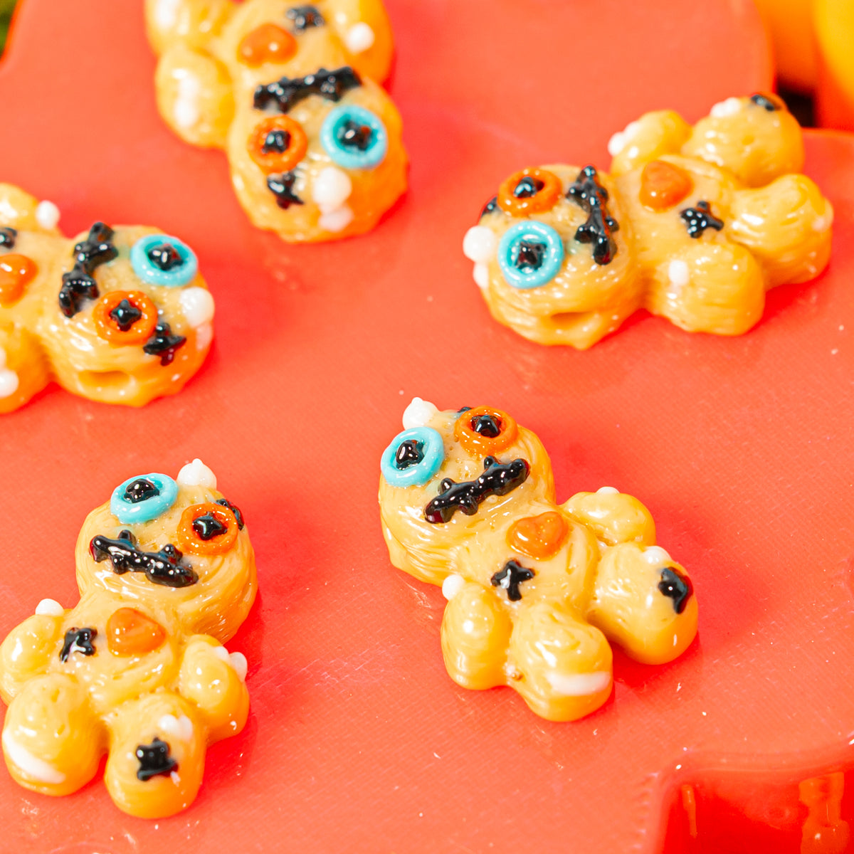 Voodoo doll kandi beads with blue and orange button eyes spread across a red riser