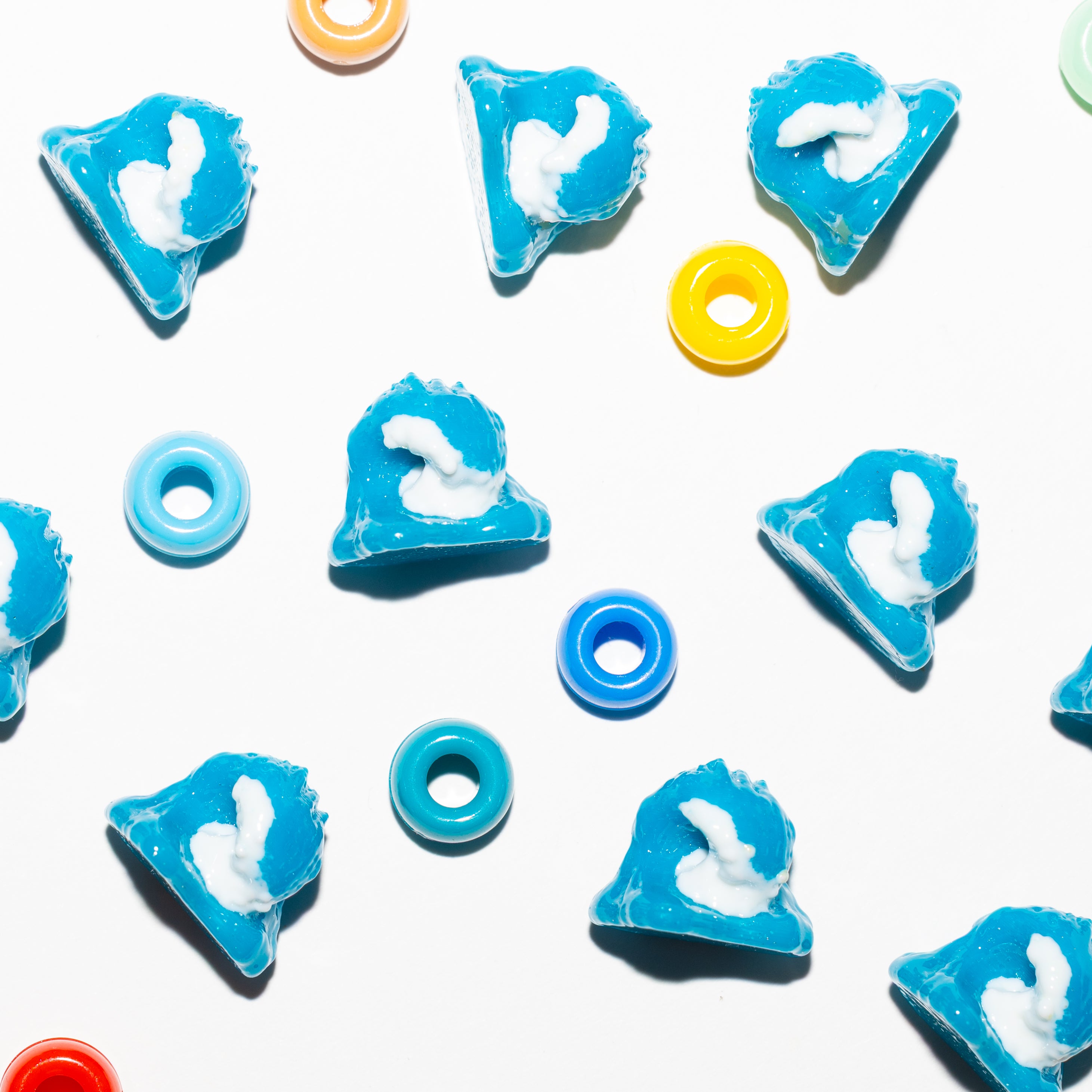 Blue and white wave kandi beads scattered on white among rainbow pony beads